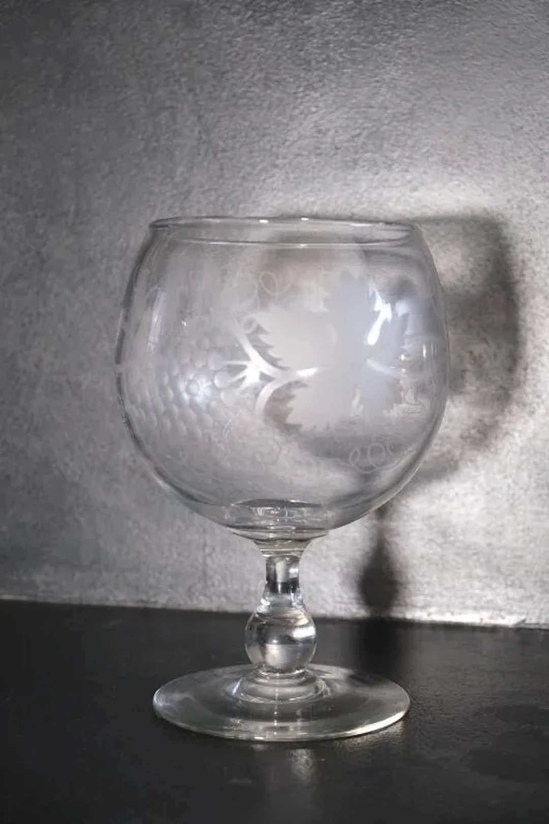A wine glass made of blown crystal and engraved with grapevine tendrils.