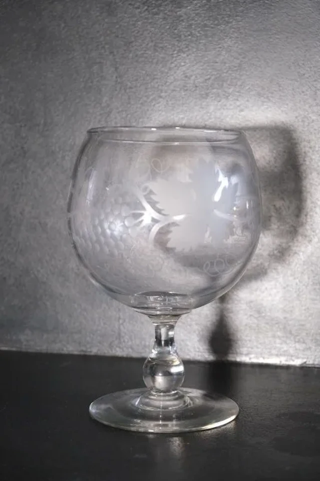A wine glass made of blown crystal and engraved with grapevine tendrils.