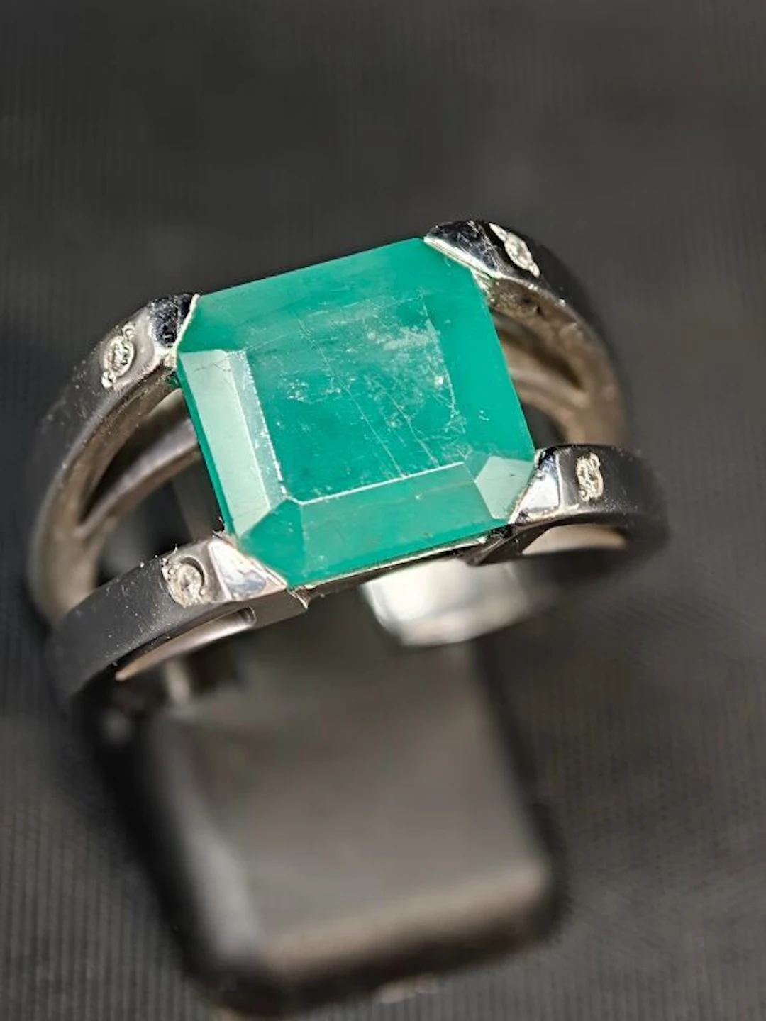 A 750‰ white gold ring set with an emerald-cut emerald, flanked by