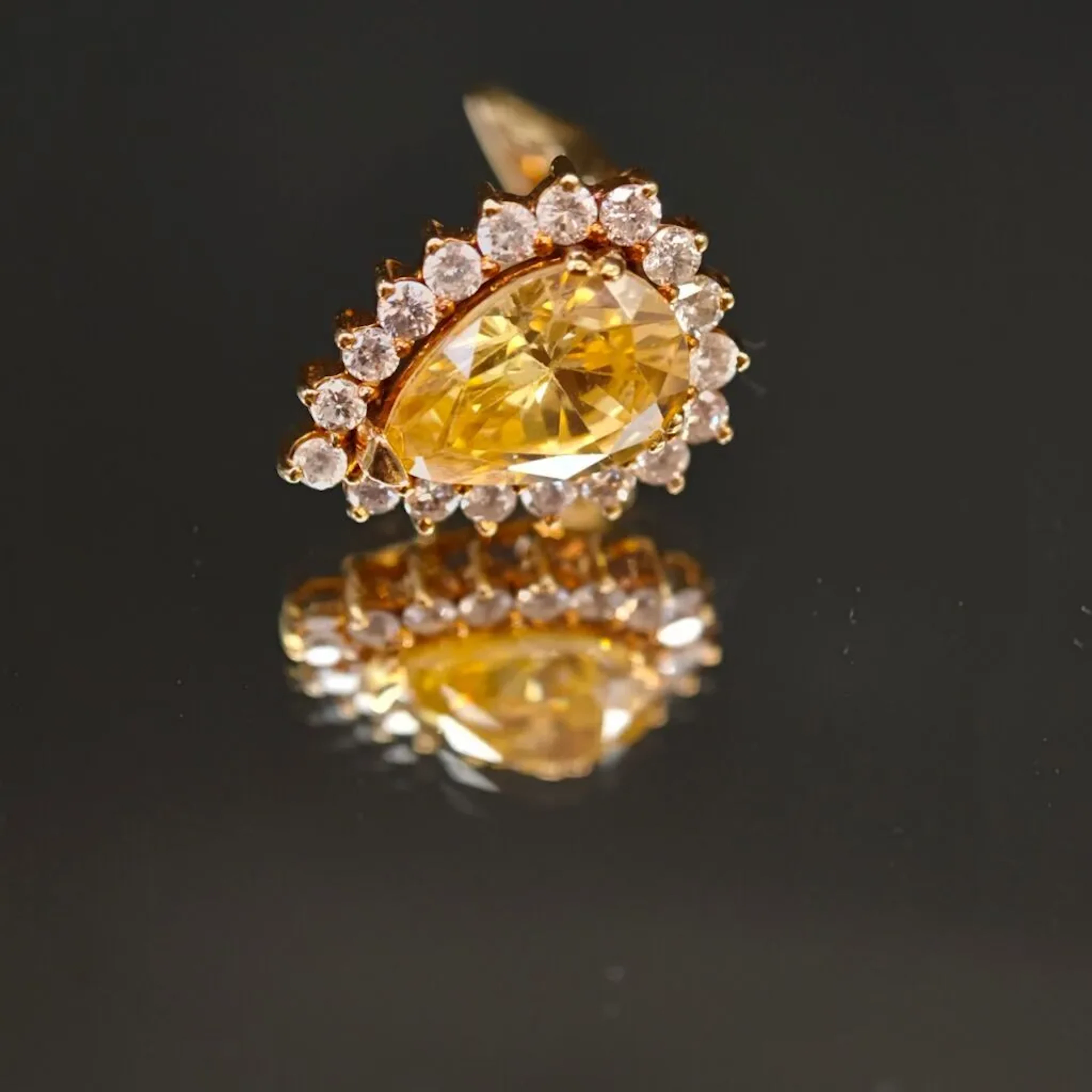 A single 750‰ yellow gold ear clip set with a pear-shaped yellow-colored