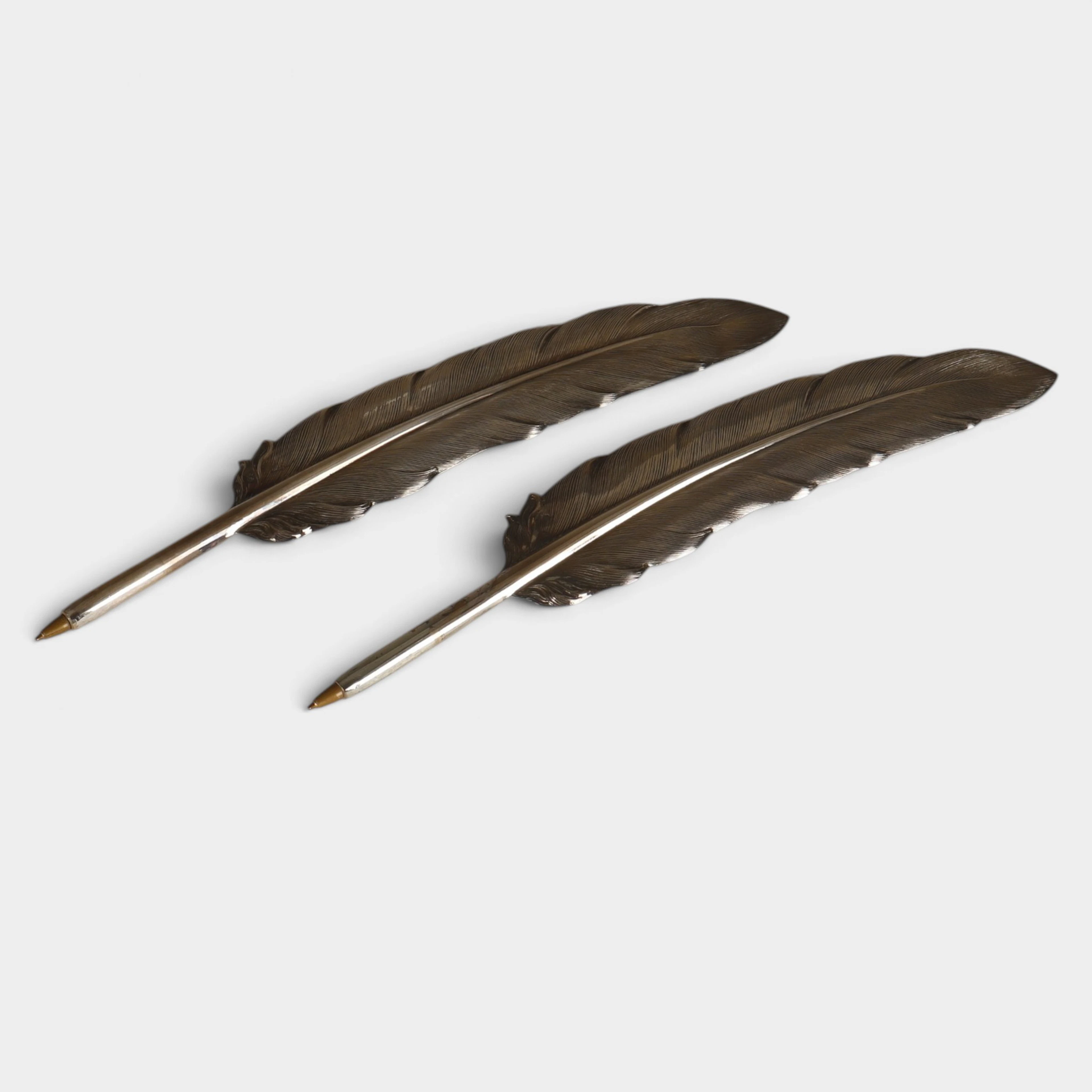Dos plumas en plata.