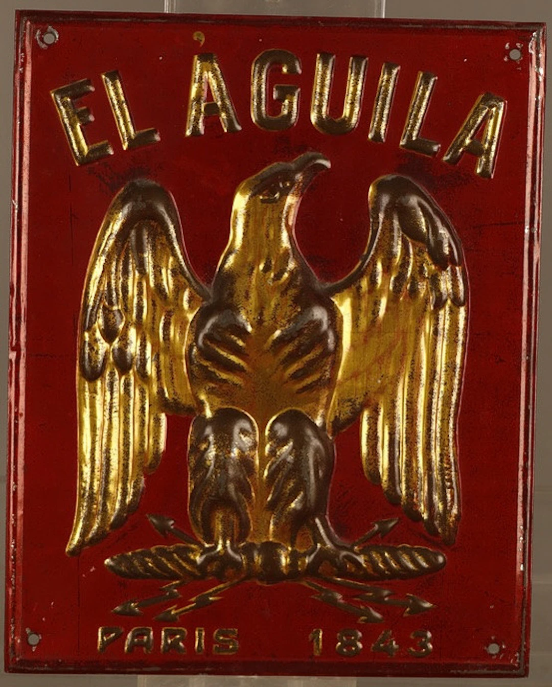 El Aguila, placa publicitaria en hojalata estampada y pintada.