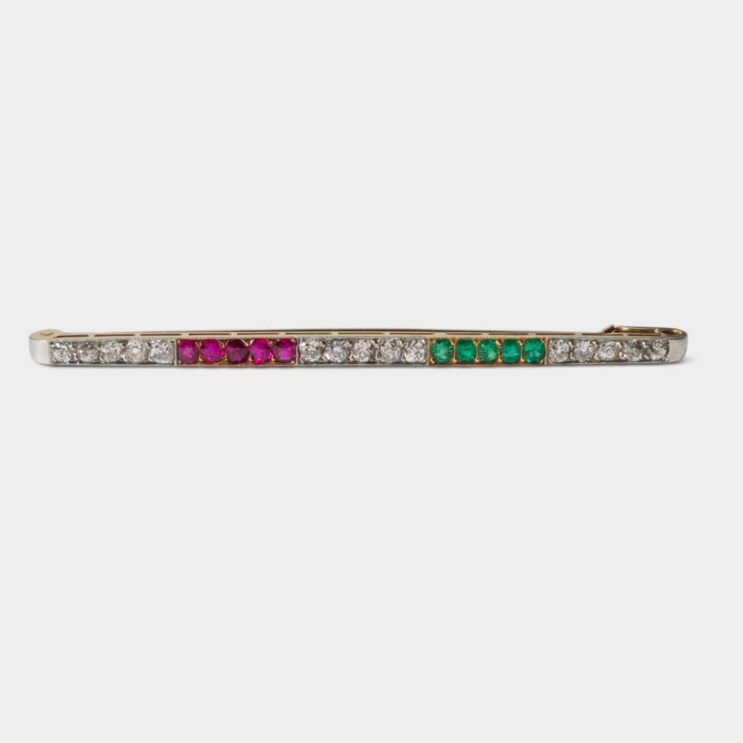 Broche aguja en oro de 18K con diamantes, rubíes y esmeraldas.