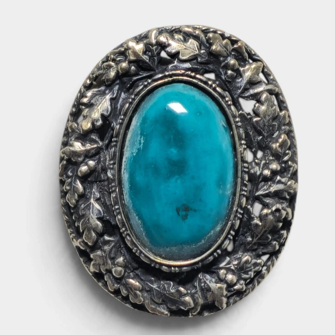 Broche en plata con piedra azul.