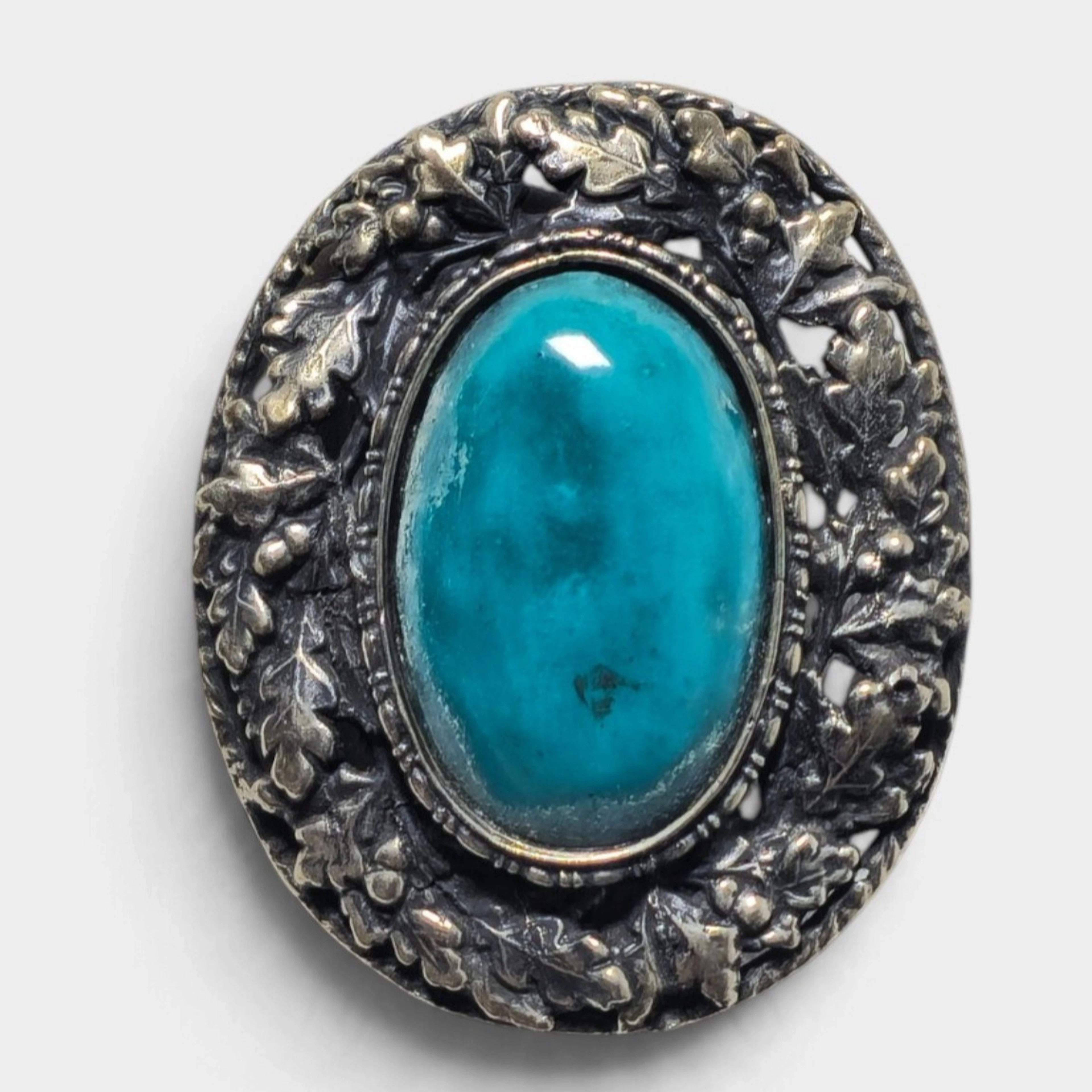 Broche en plata con piedra azul.