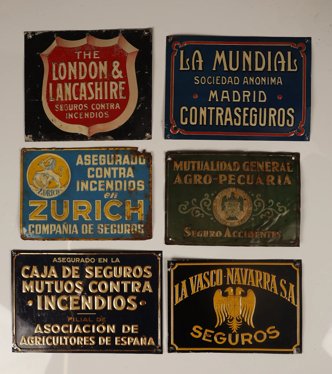 La Mundial y otras. 6 placas publicitarias en hojalata estampada y pintada.