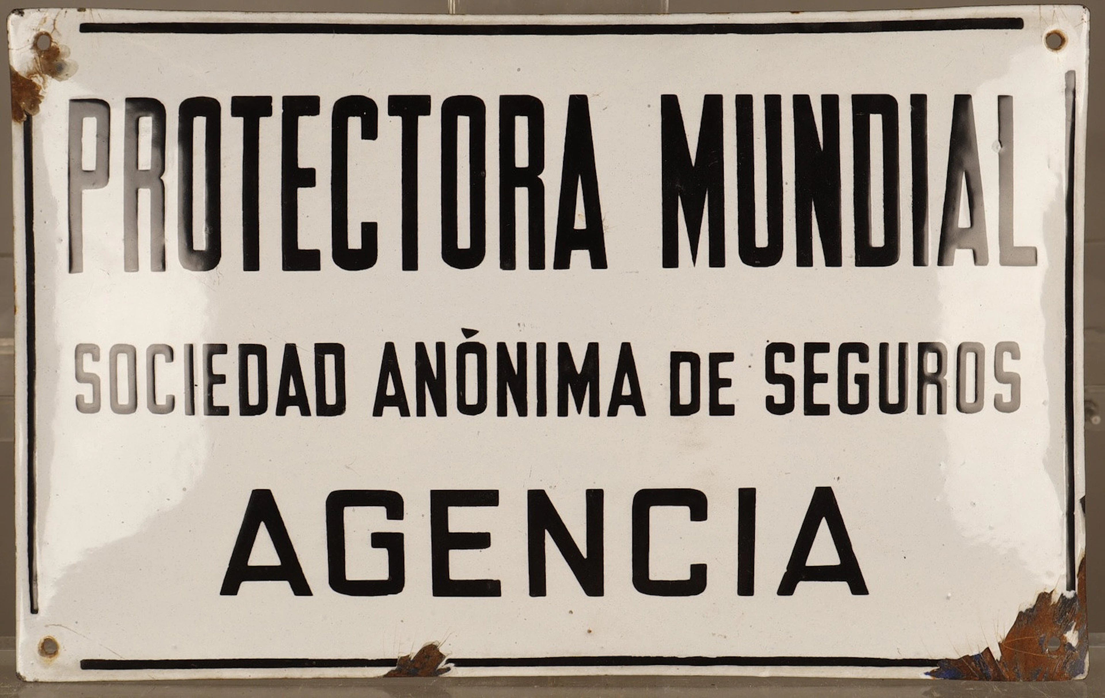 Protectora Mundial, placa publicitaria en hojalata estampada y pintada.