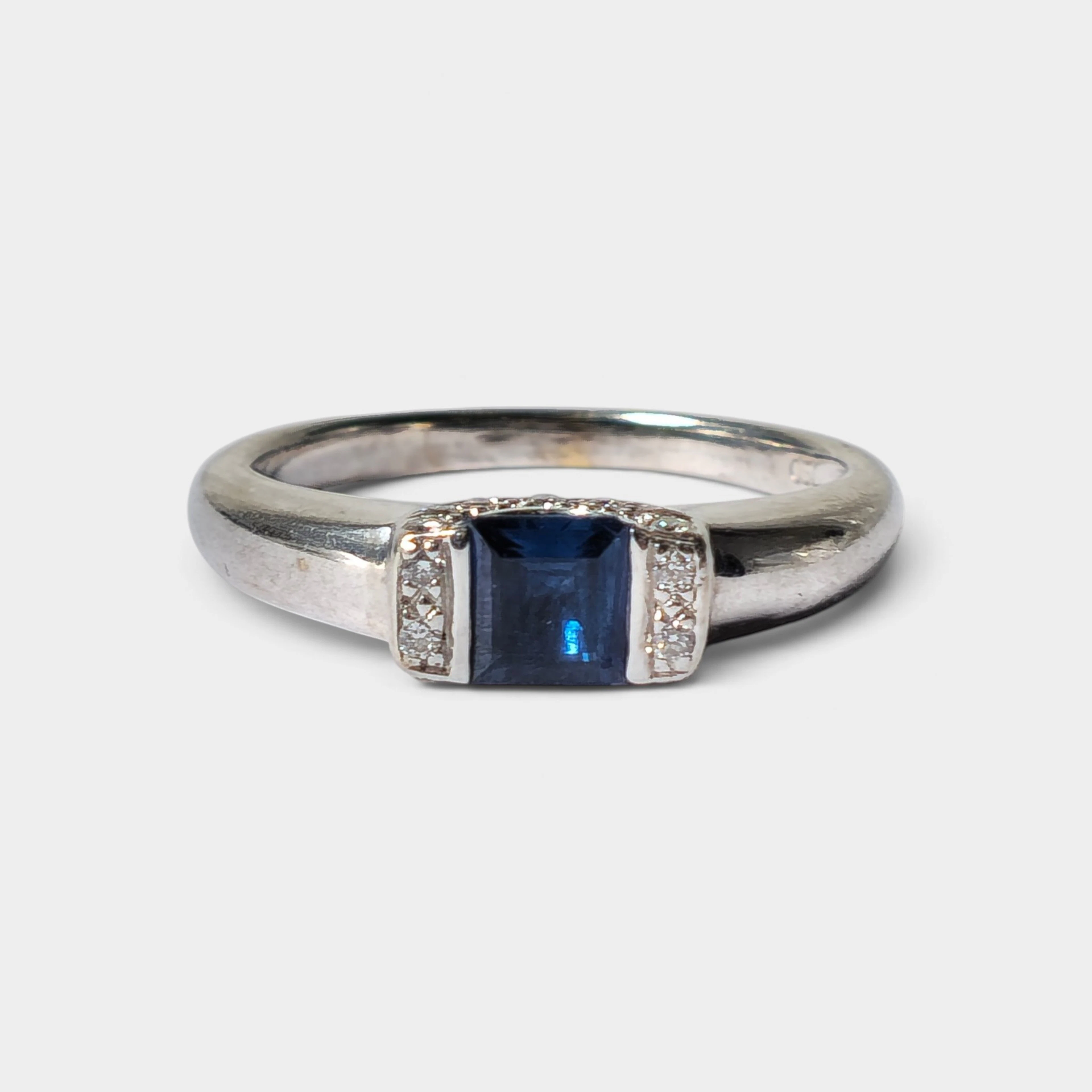 Anillo en oro blanco con zafiro y diamantes laterales.