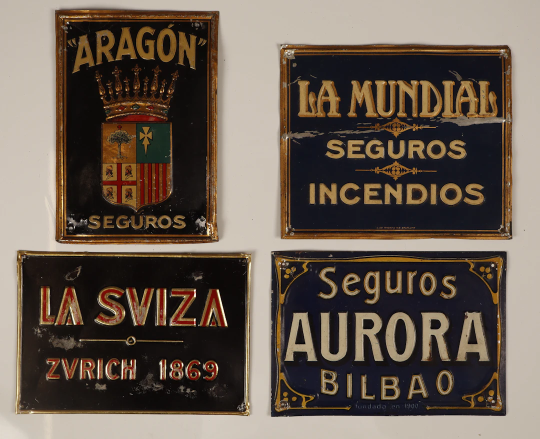 La Suiza y otras. 4 placas publicitarias en hojalata estampada y pintada.