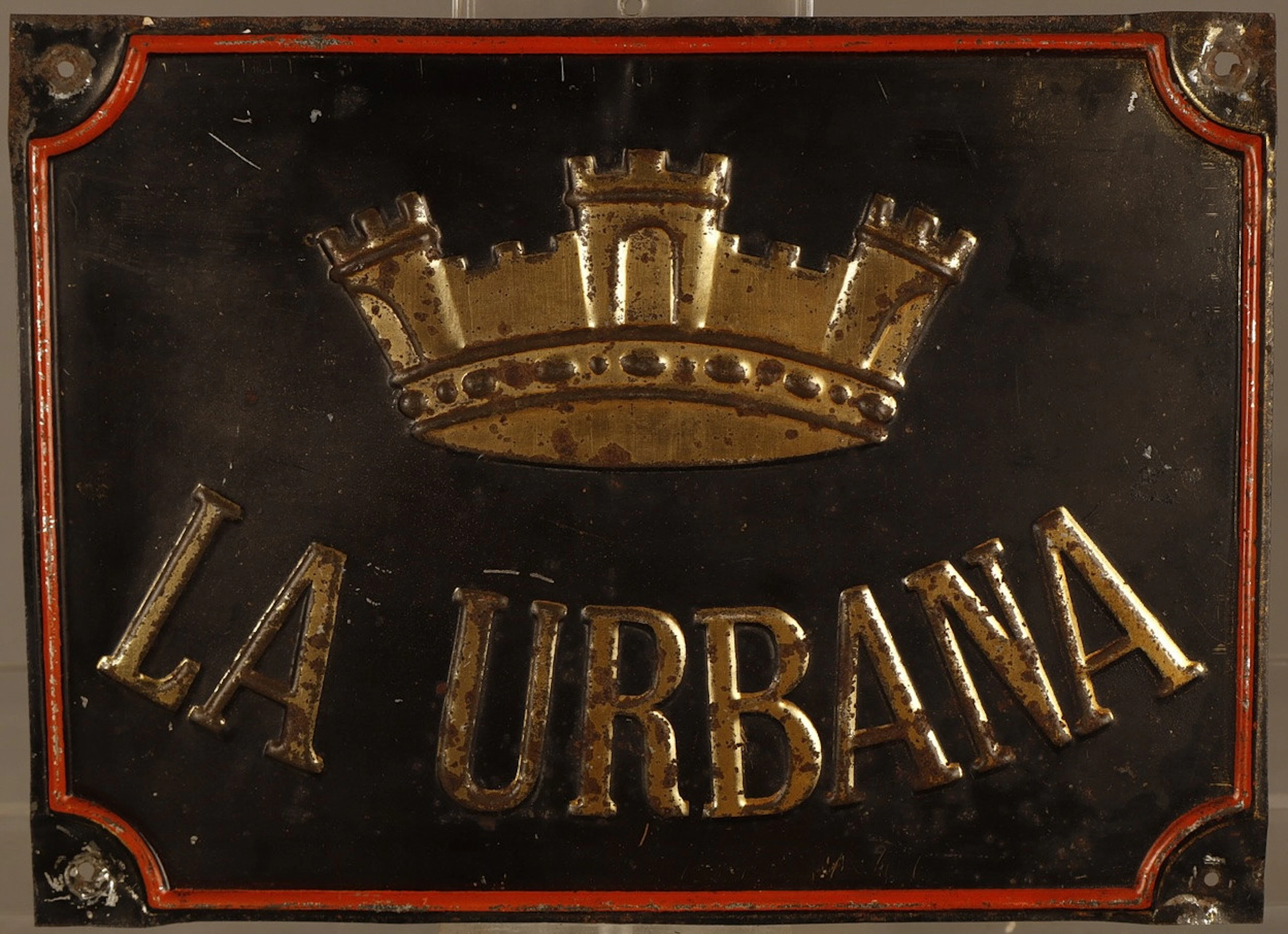 La Urbana, placa publicitaria en hojalata estampada y pintada.