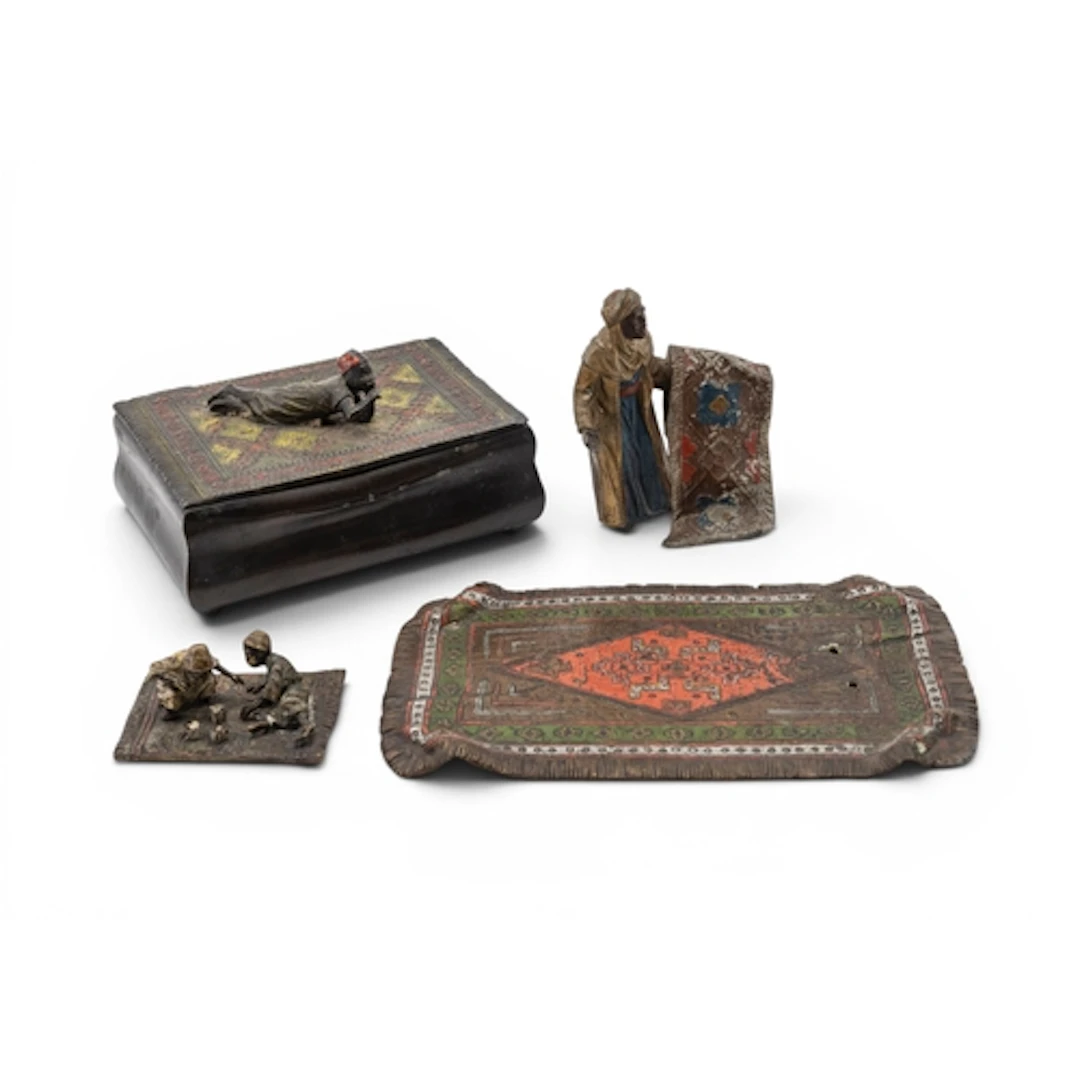 A BERGMAN STYLE BRONZE of two boys playing dice on a carpet,...