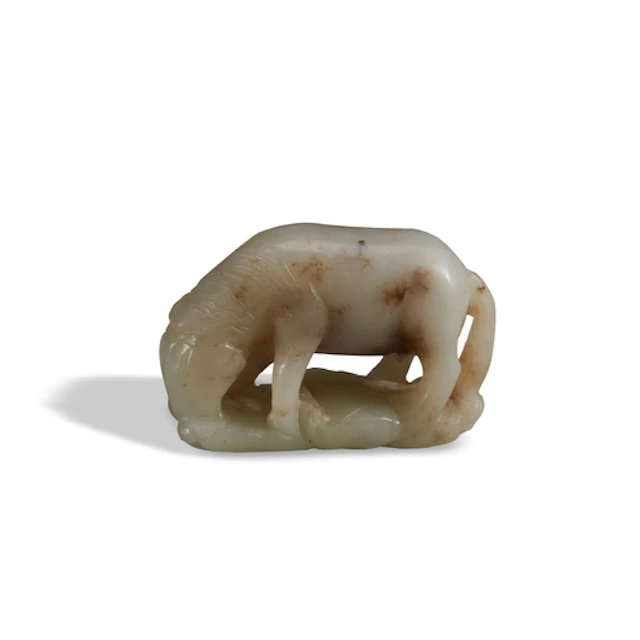 A MOTTLED WHITE-CELADON JADE CARVING OF A HORSE ON WAVES 17...