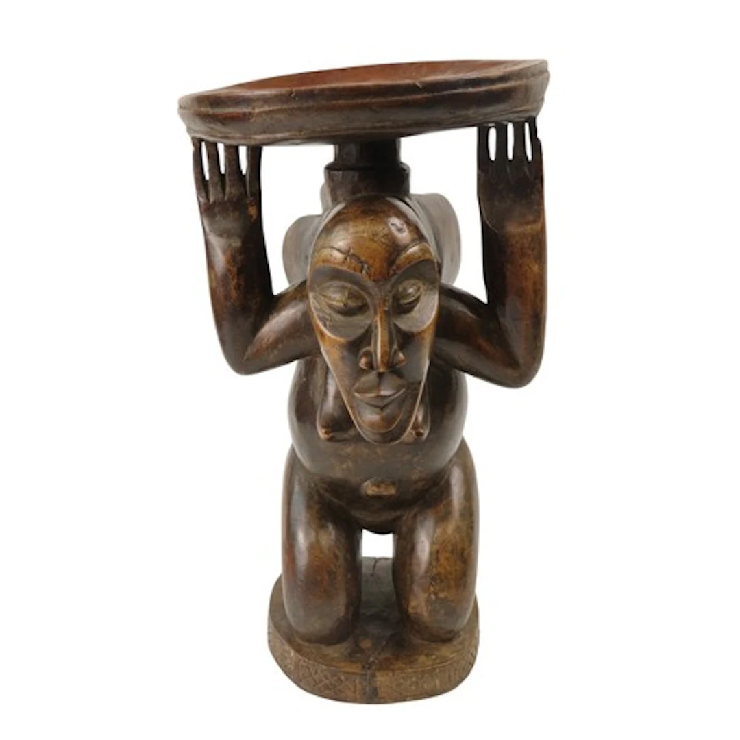 A LUBA CARVED WOODEN STOOL of a kneeling female figure, her ...