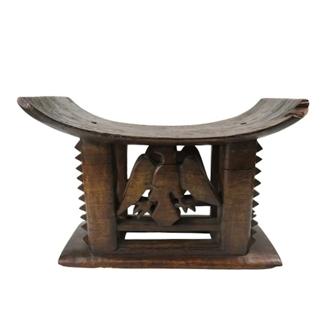 AN ASHANTI CARVED WOODEN STOOL, the curved top over serrated...