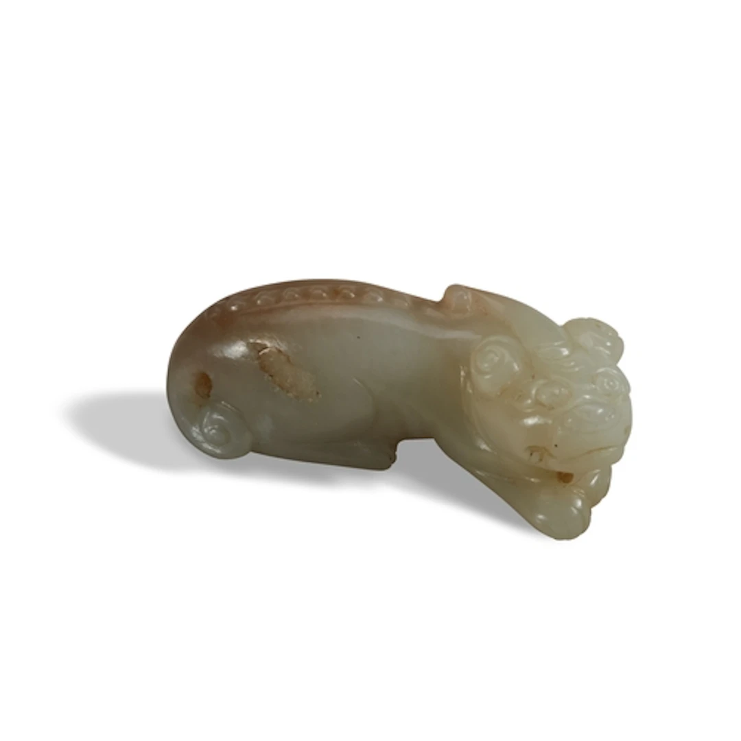A CELADON AND RUSSET JADE 'HORNED-LION' PENDANT QING DYNASTY...