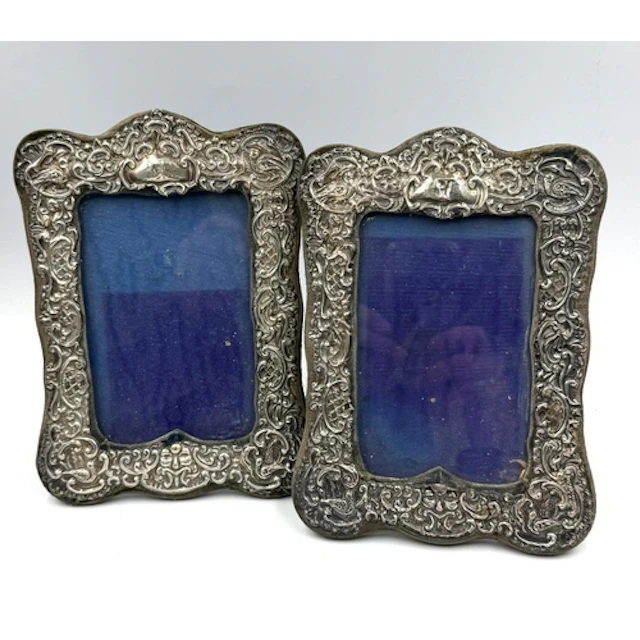 A pair of ornate silver easel photograph frames with scrolli...