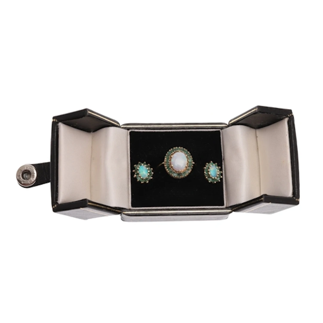 AN OPAL AND EMERALD CLUSTER RING. the oval-shaped solid whit...