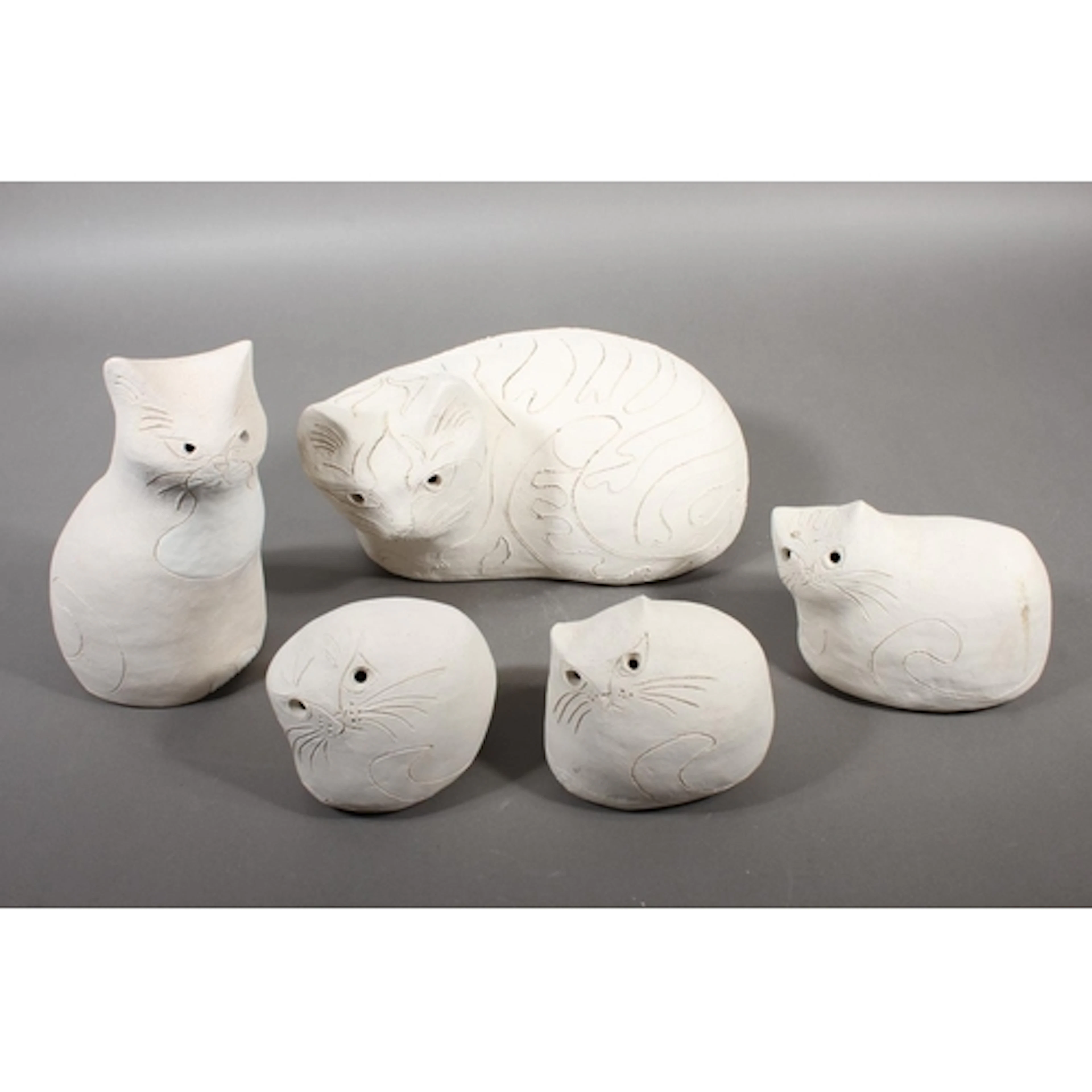 Oxshott Pottery, five unglazed biscuit fired models of cats,...