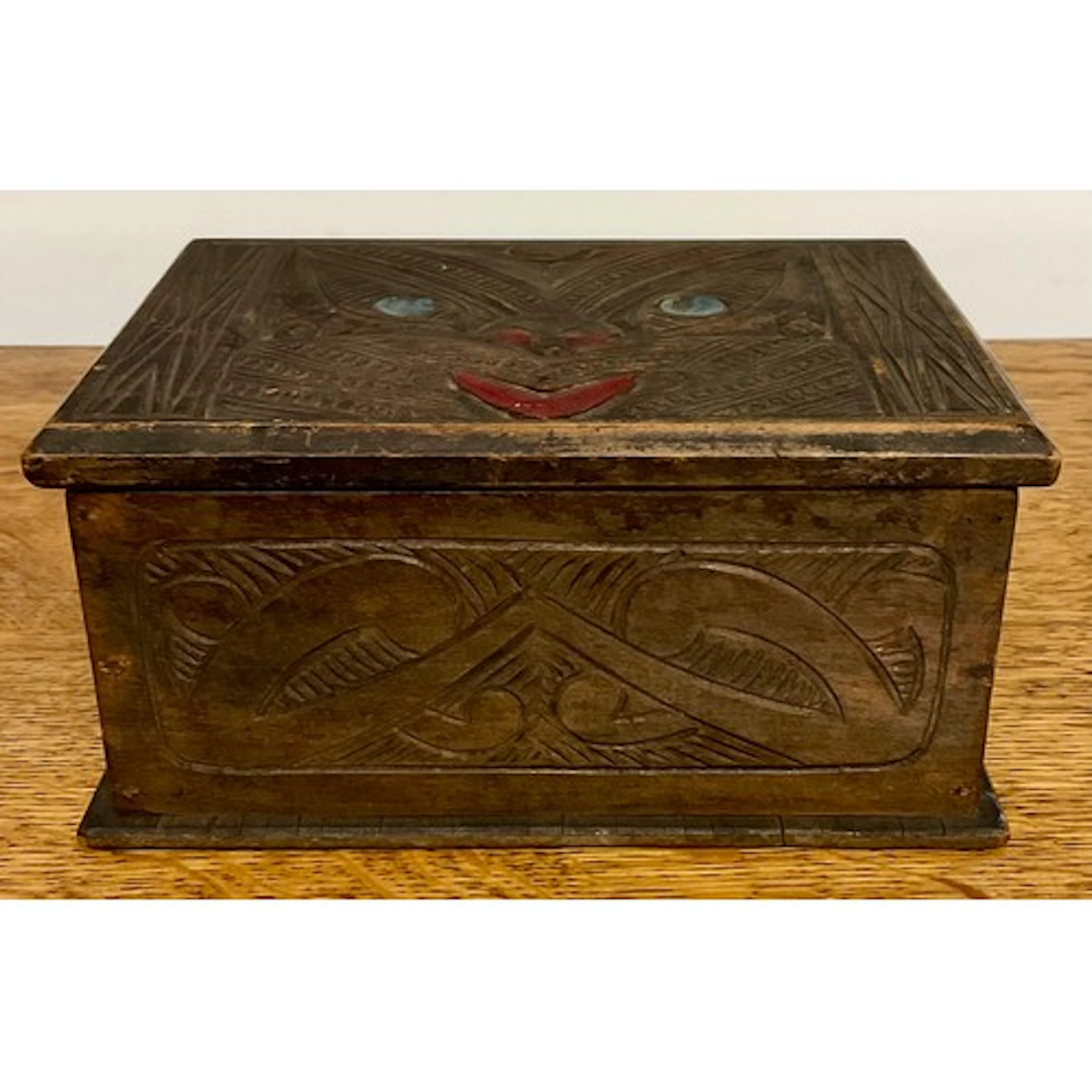 A Maori box, hinged cover carved with a wheku, inlaid paua s...