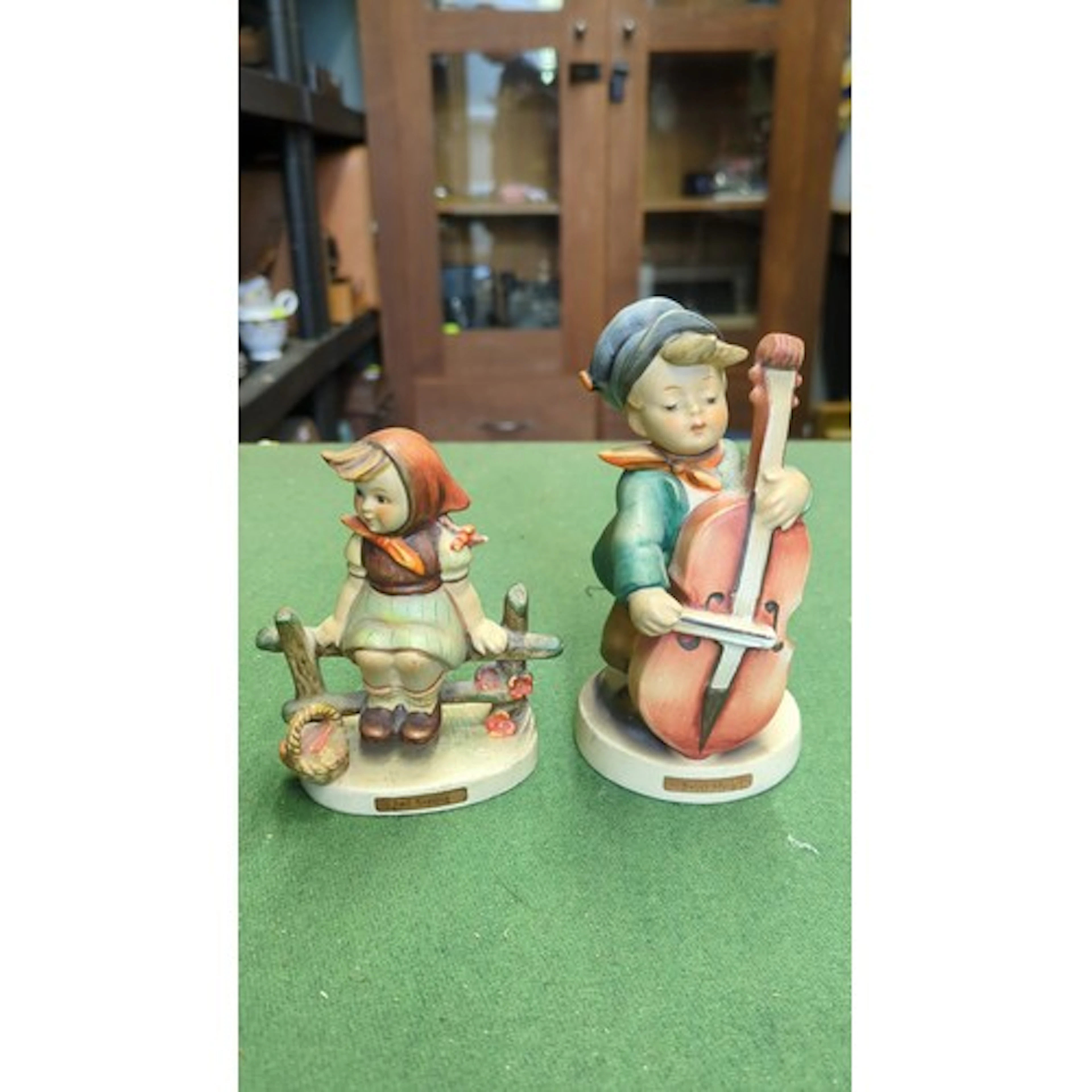 A pair of German porcelain Hummel-type figures: a seated gir...