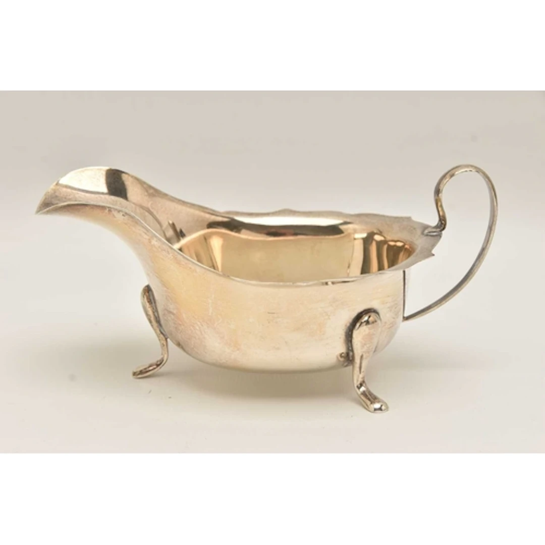 A GEORGE V SILVER SAUCE BOAT, polished form with wavy rim an...