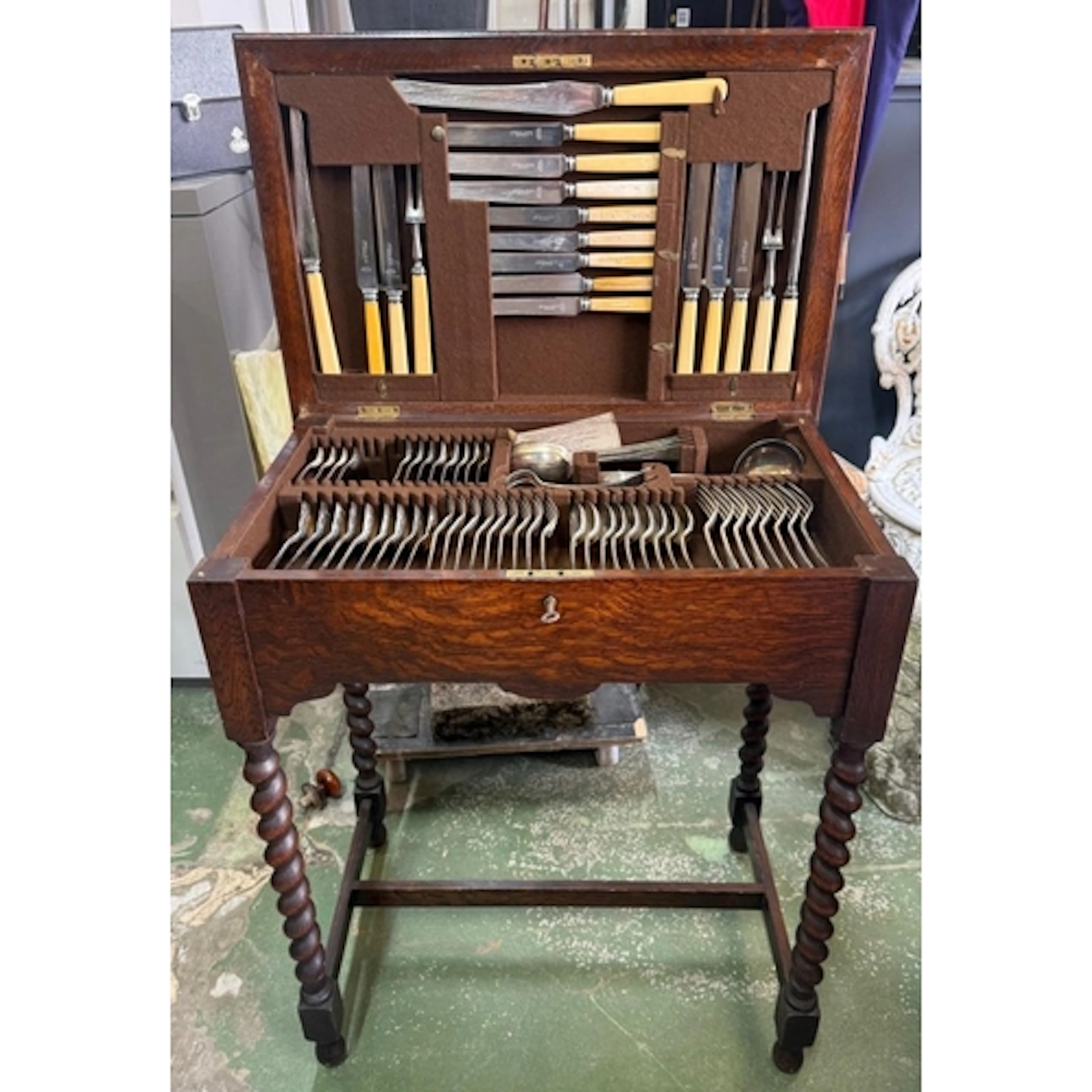 An oak cuttlery table on barley twist legs containing a quan...