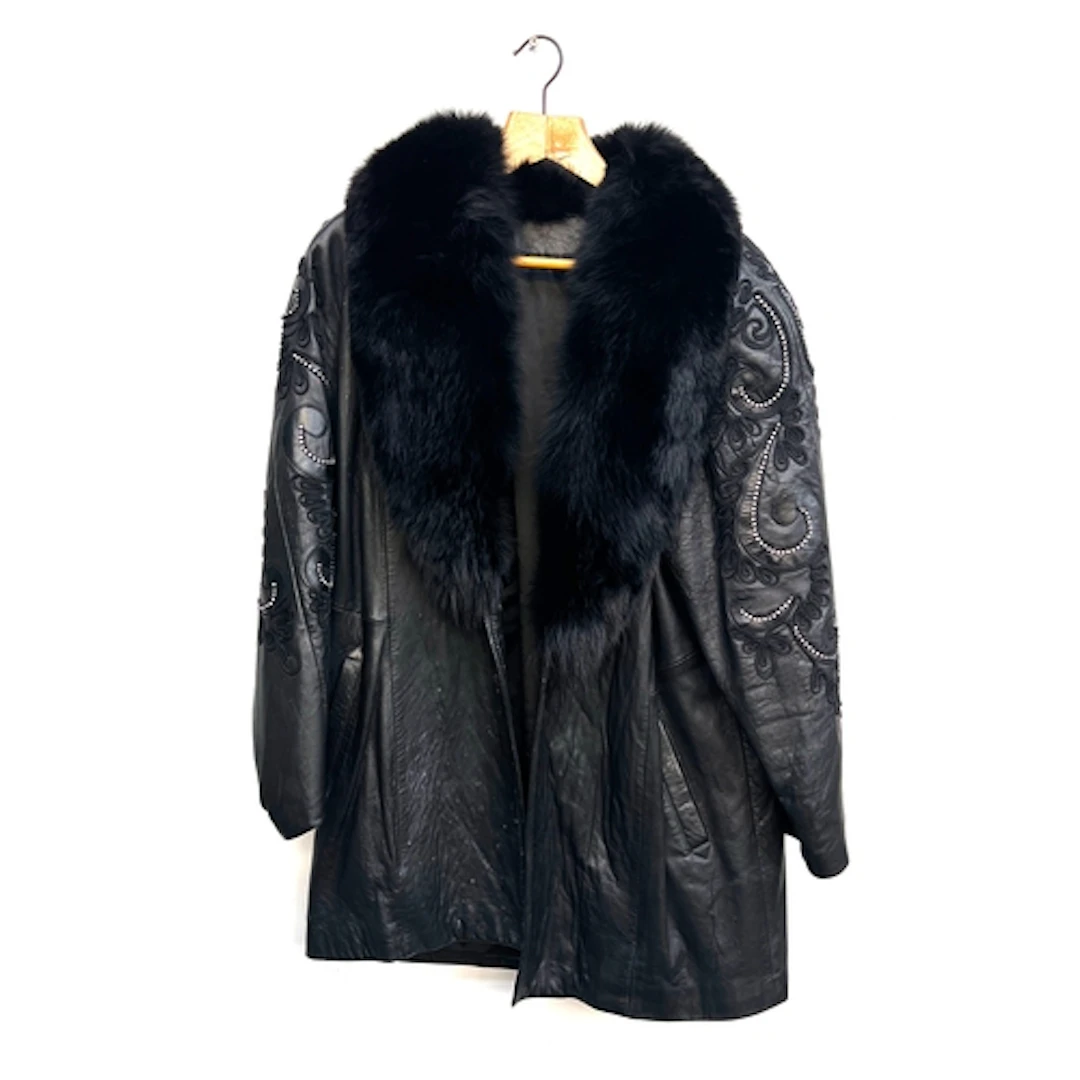 A black leather coat with fur collar and rhinestone detail t...