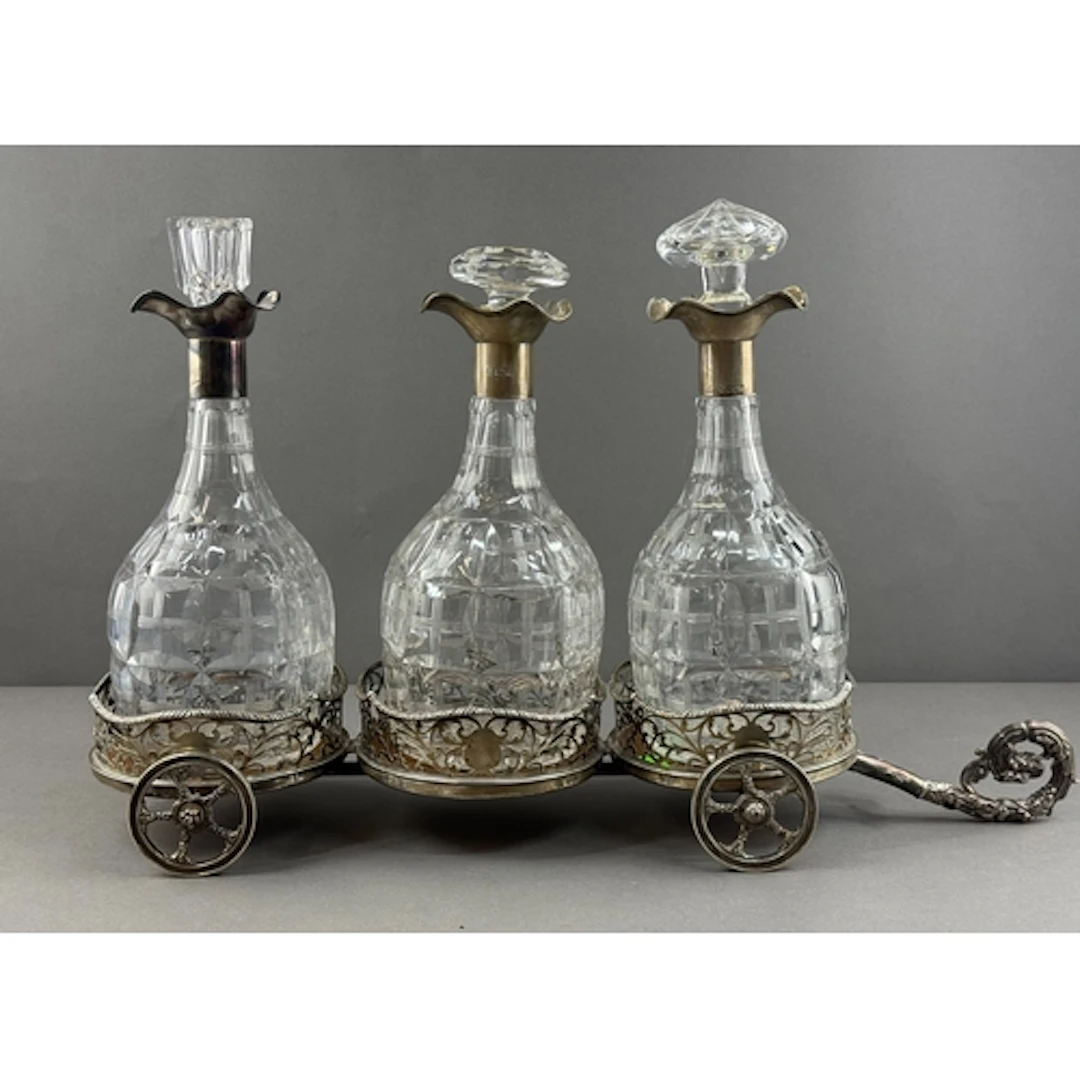 Silver: a triple decanter carriage, each pierced coaster hal...