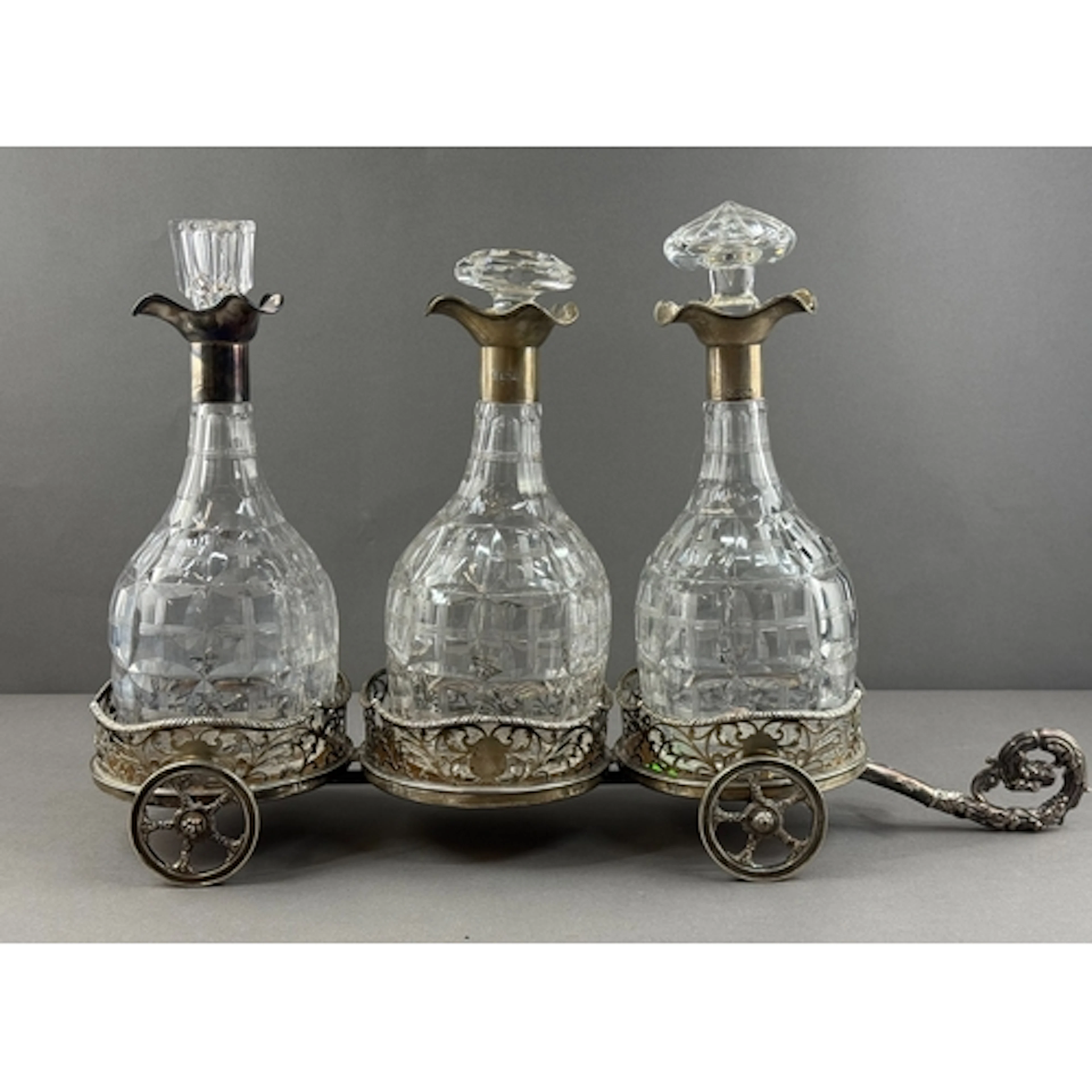 Silver: a triple decanter carriage, each pierced coaster hal...