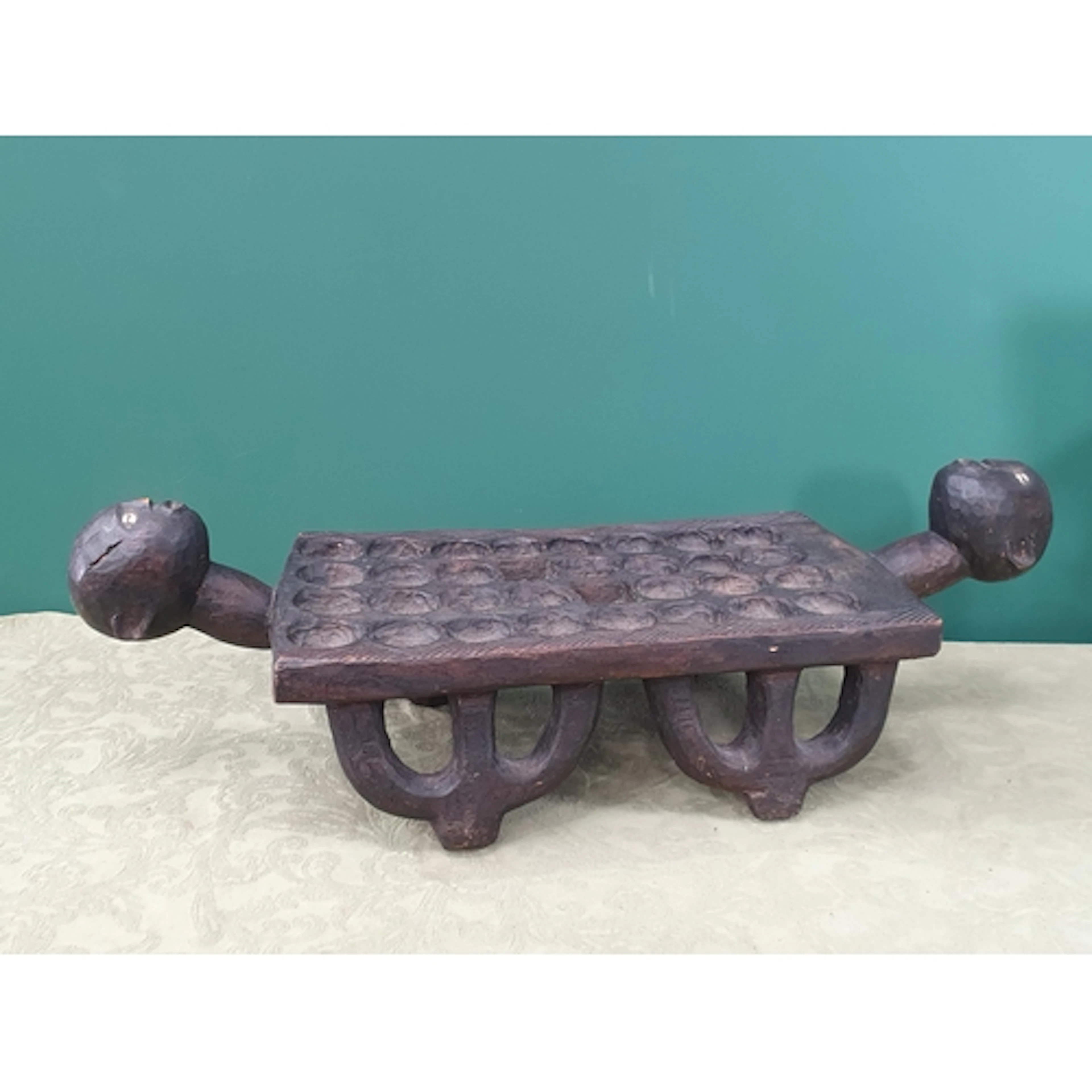 A vintage carved wood African Mancala Game Board, raised on ...