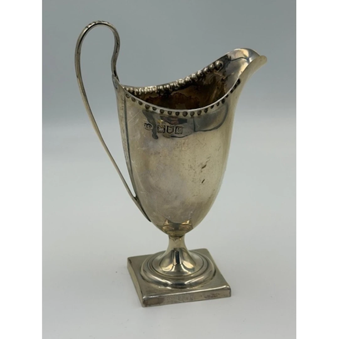 A helmet shaped silver cream jug on a square pedestal foot, ...