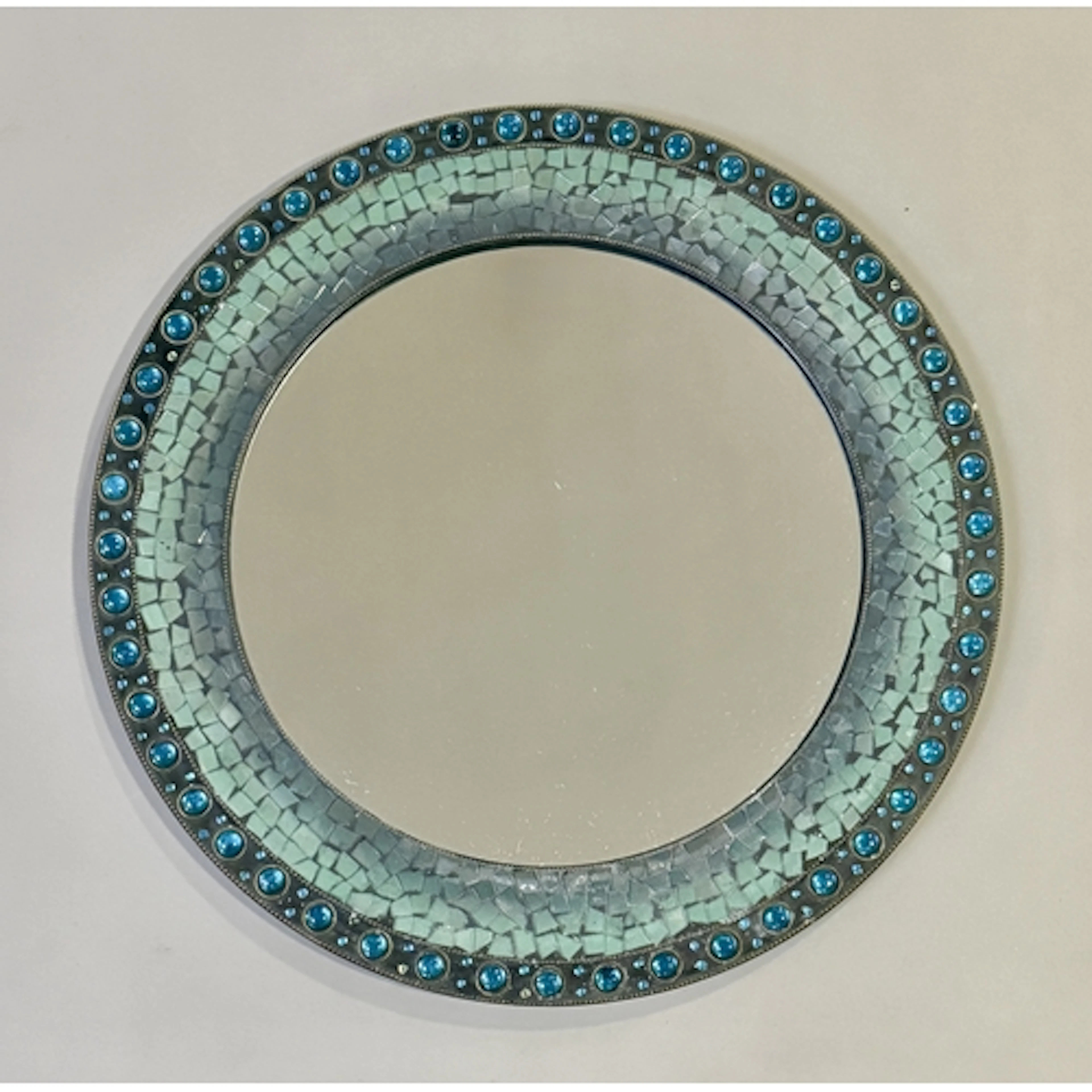 A circular iridescent glass mosaic, bead and brass framed mi...