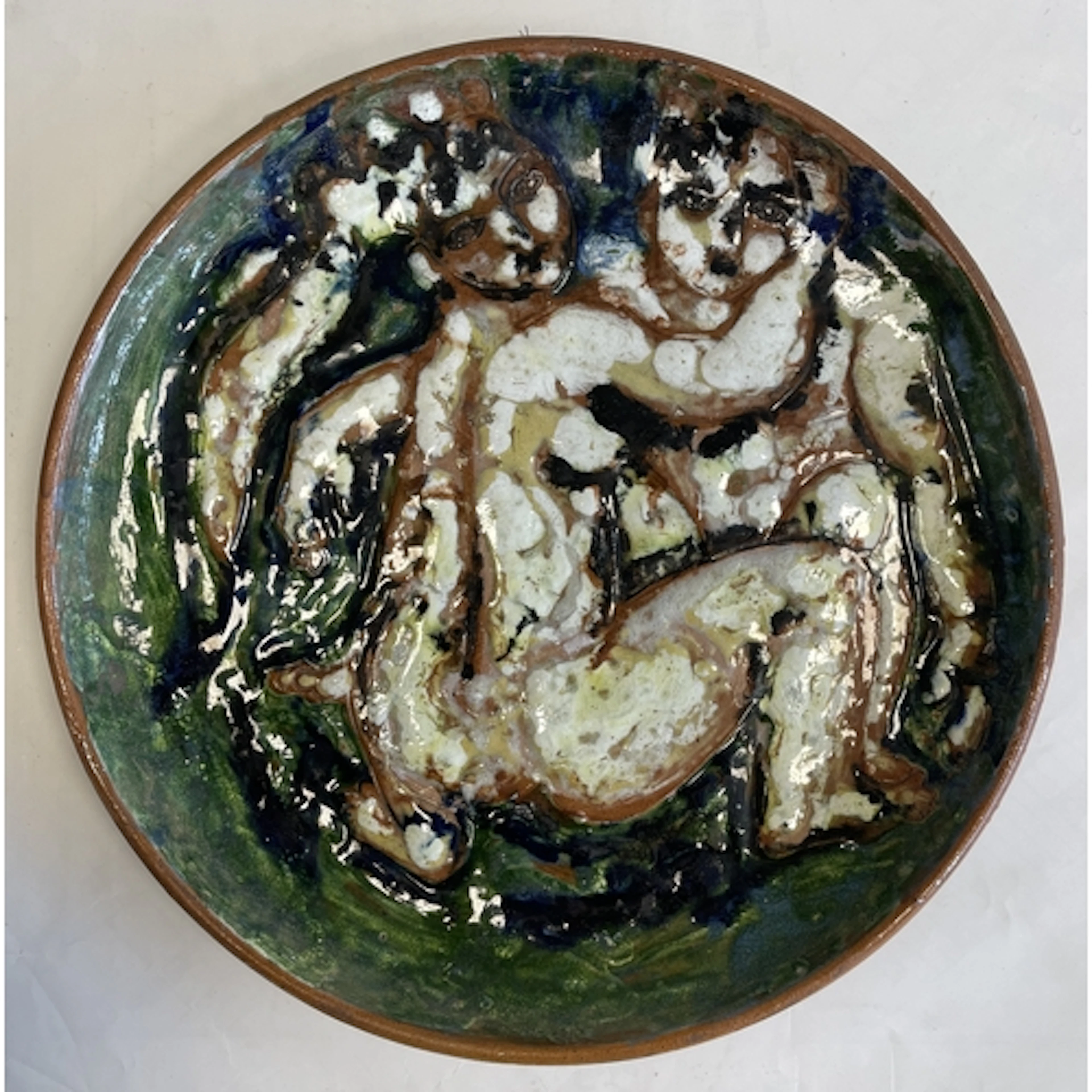 A large terracotta glazed wall charger embellished with surr...