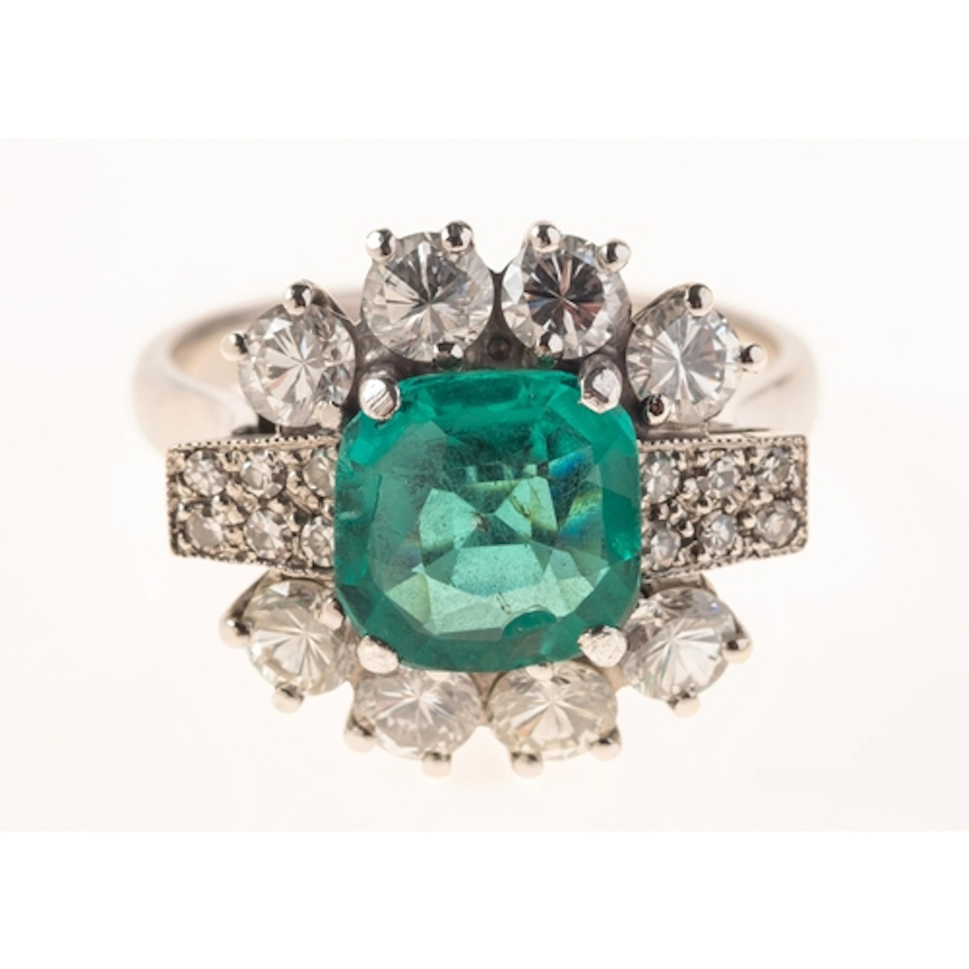 A 1980's emerald and diamond cluster ring, claw set to the c...