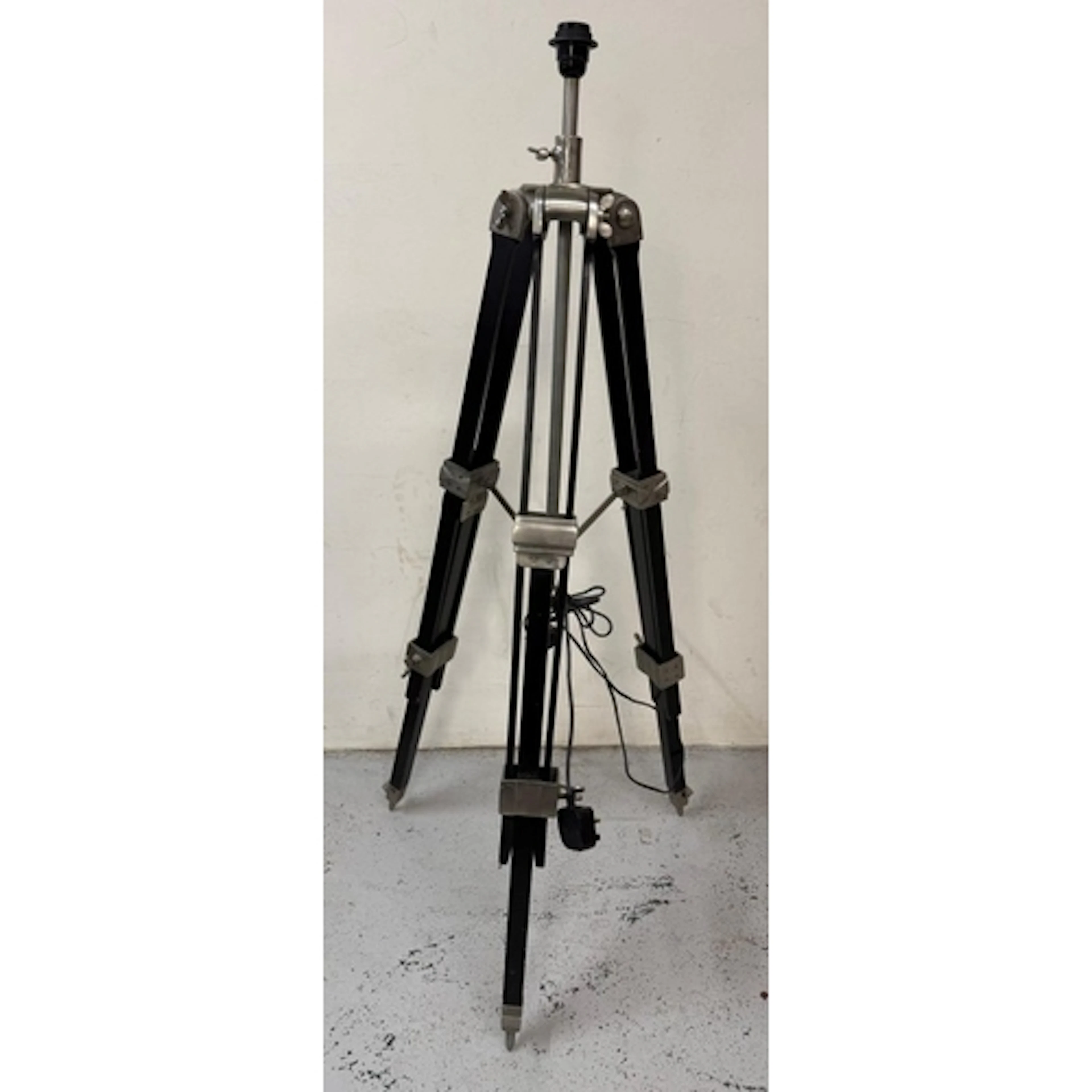 An adjustable surveyor-style tripod floor lamp with black wo...