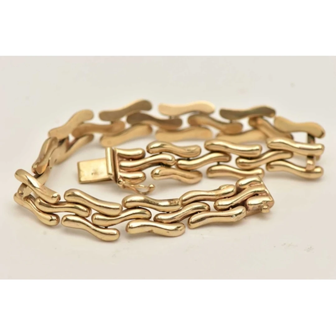A 9CT GOLD LINE BRACELET, designed as wavy links, fitted wit...
