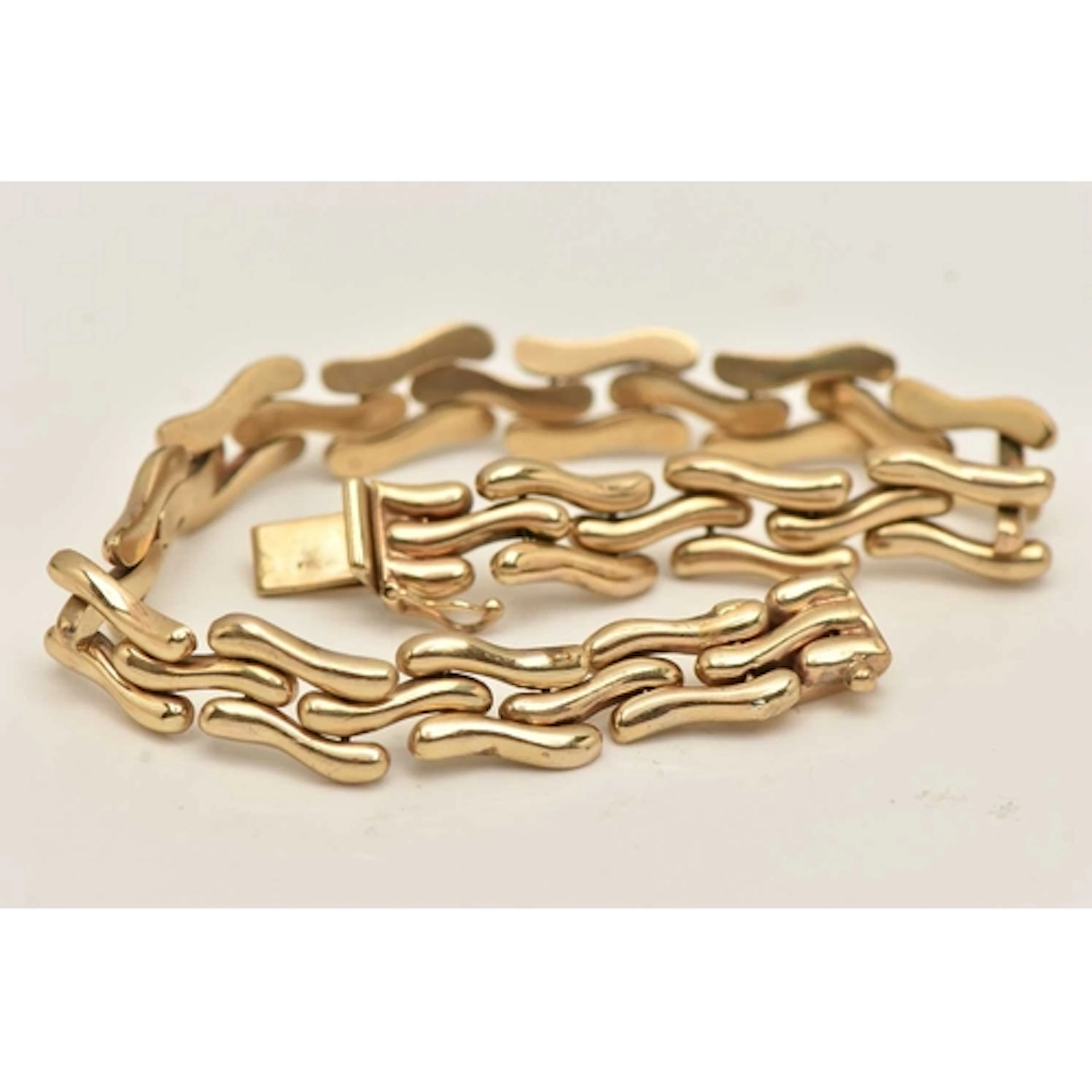 A 9CT GOLD LINE BRACELET, designed as wavy links, fitted wit...