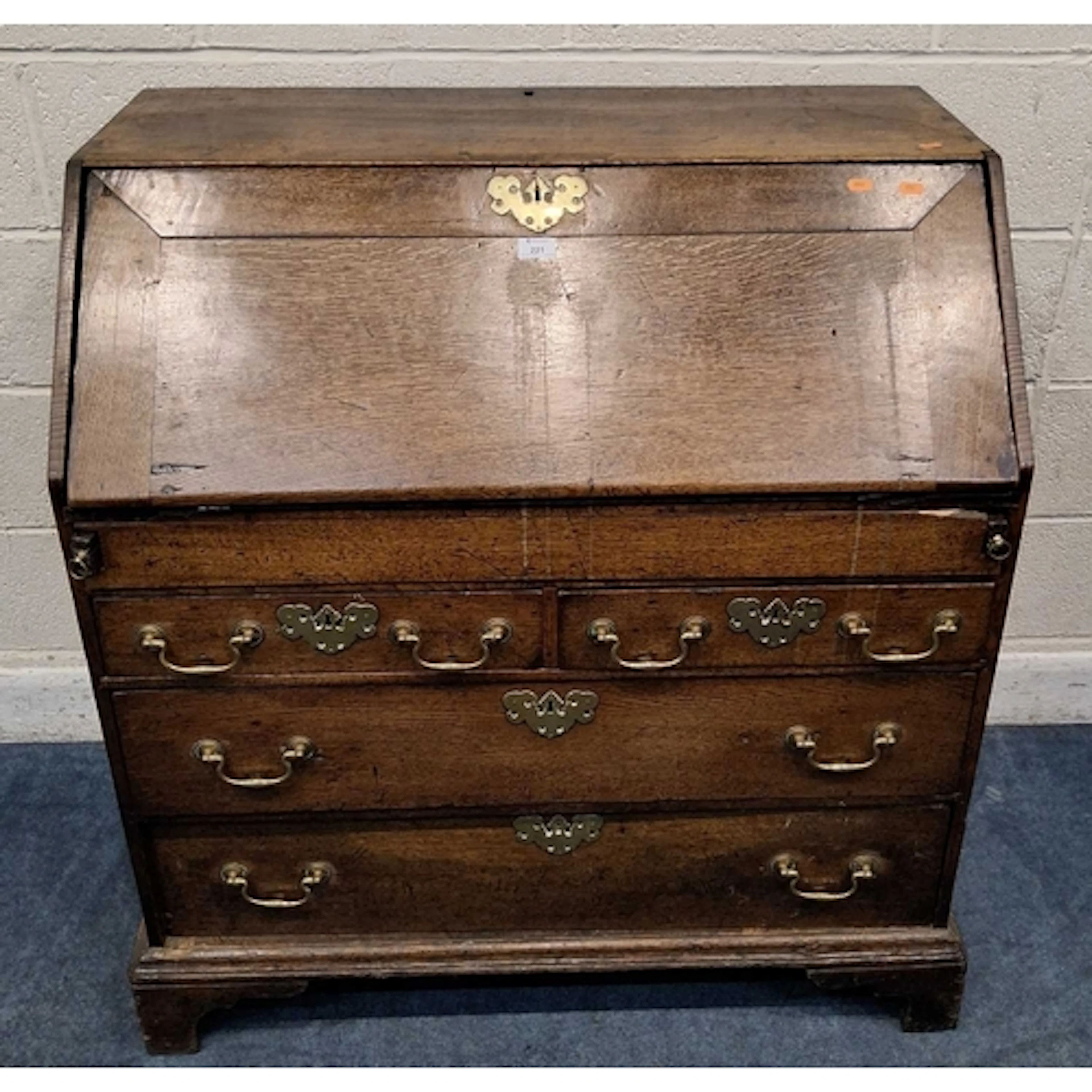 A GEORGIAN OAK BUREAU, the fall front door enclosing a fitte...
