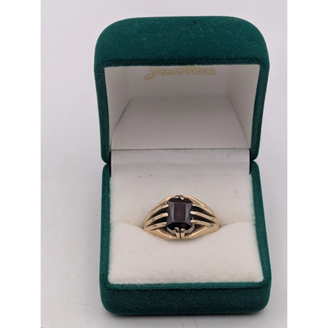 A 9ct yellow gold and garnet ring, featuring an emerald cut,...