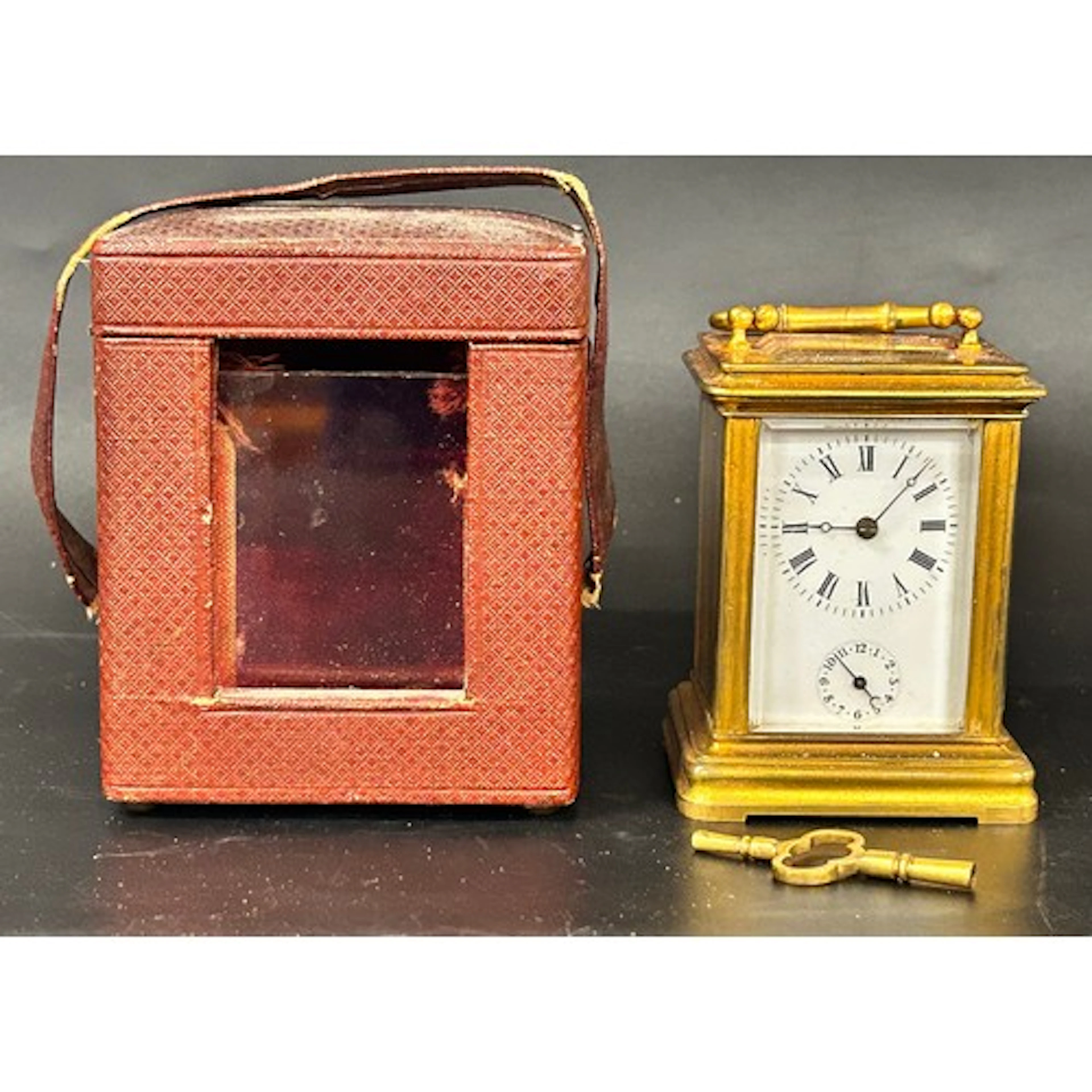A small brass carriage clock, unmarked, with key, in leather...