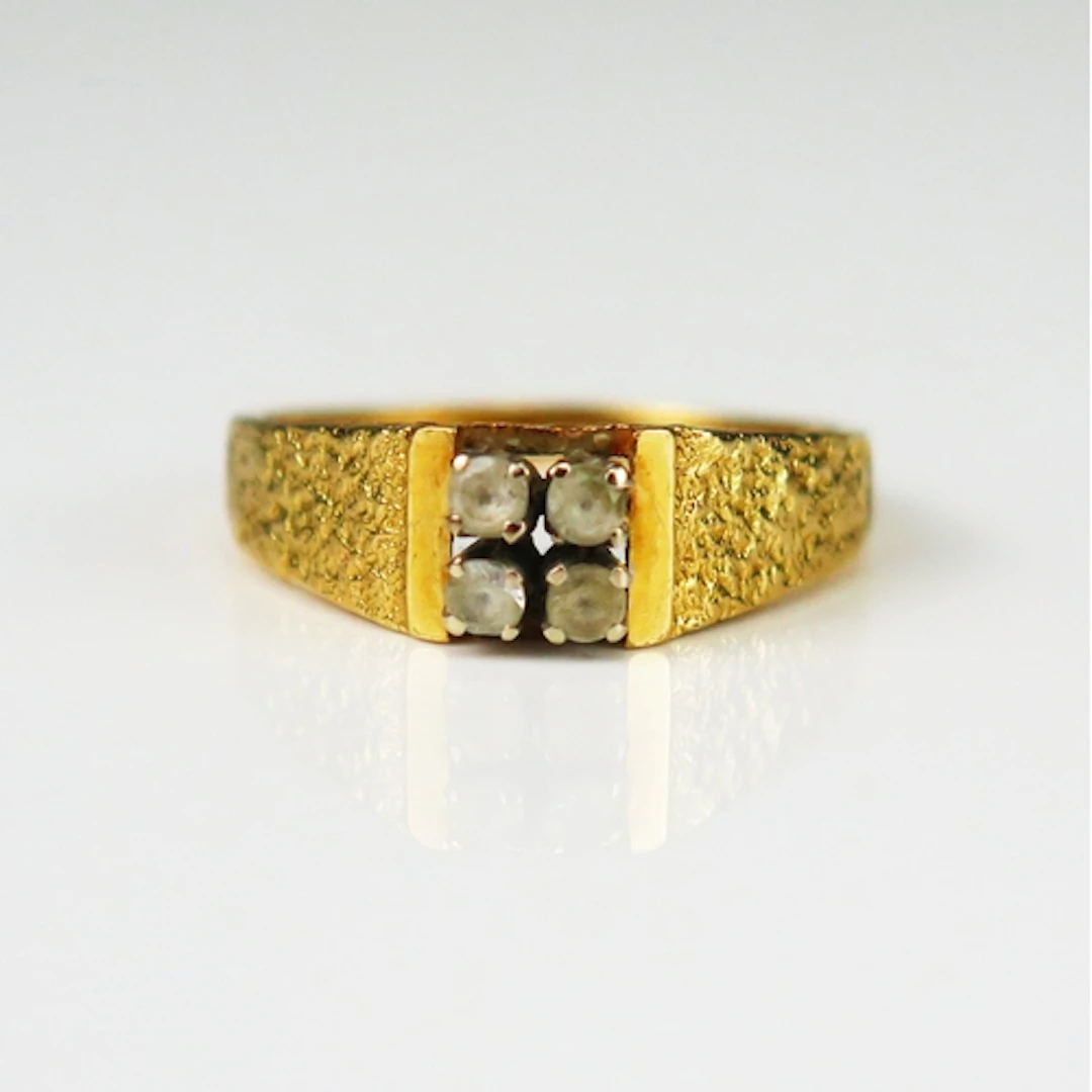 A 1970's precious yellow metal ring set with four white gems...