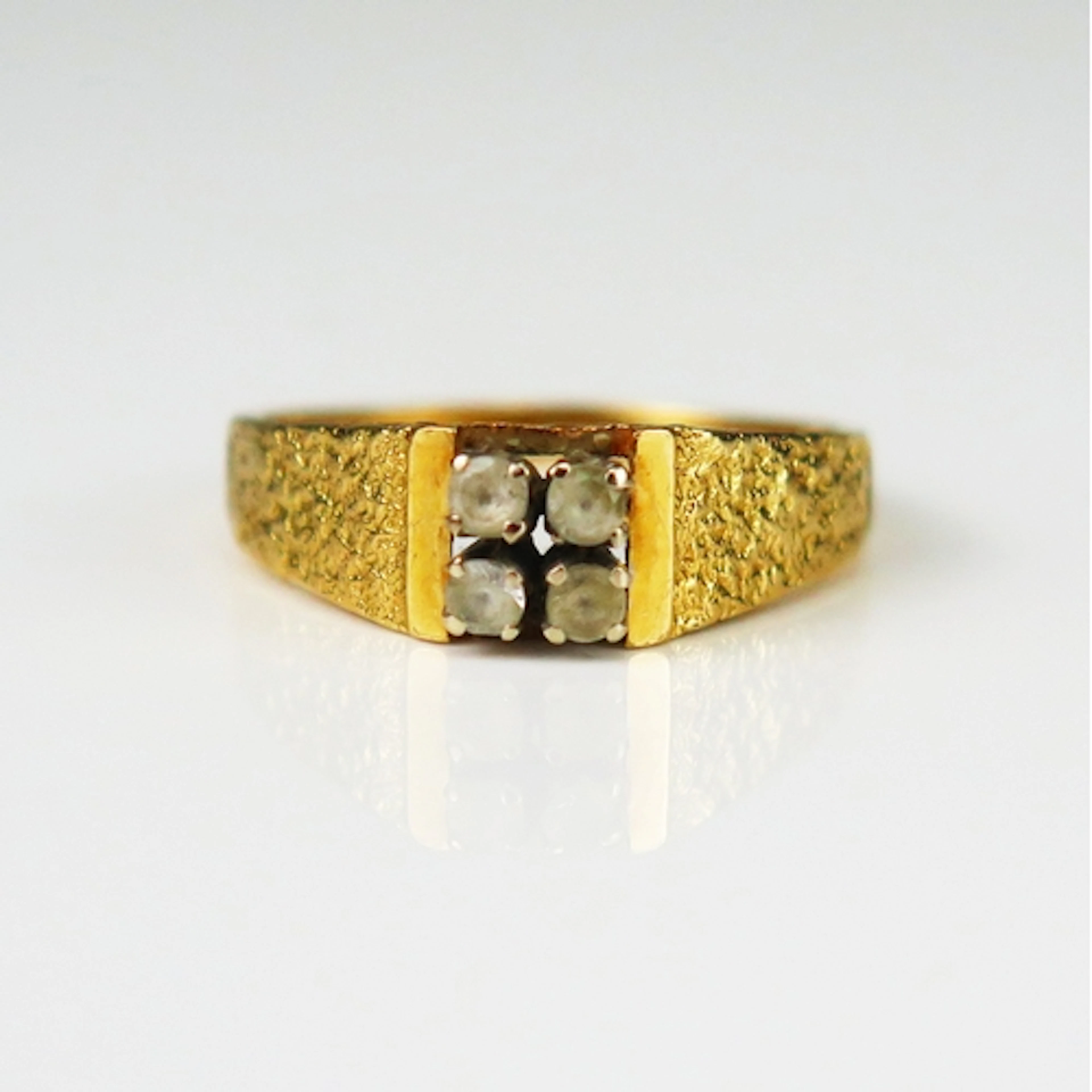 A 1970's precious yellow metal ring set with four white gems...