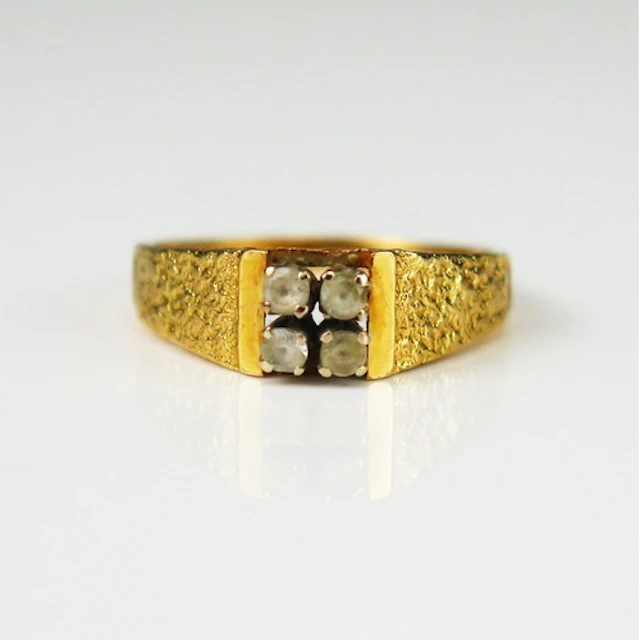 A 1970's precious yellow metal ring set with four white gems...