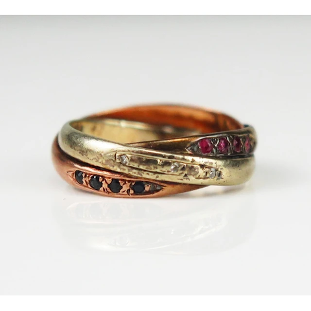 A sapphire, ruby and diamond entwined three shank ring in a ...