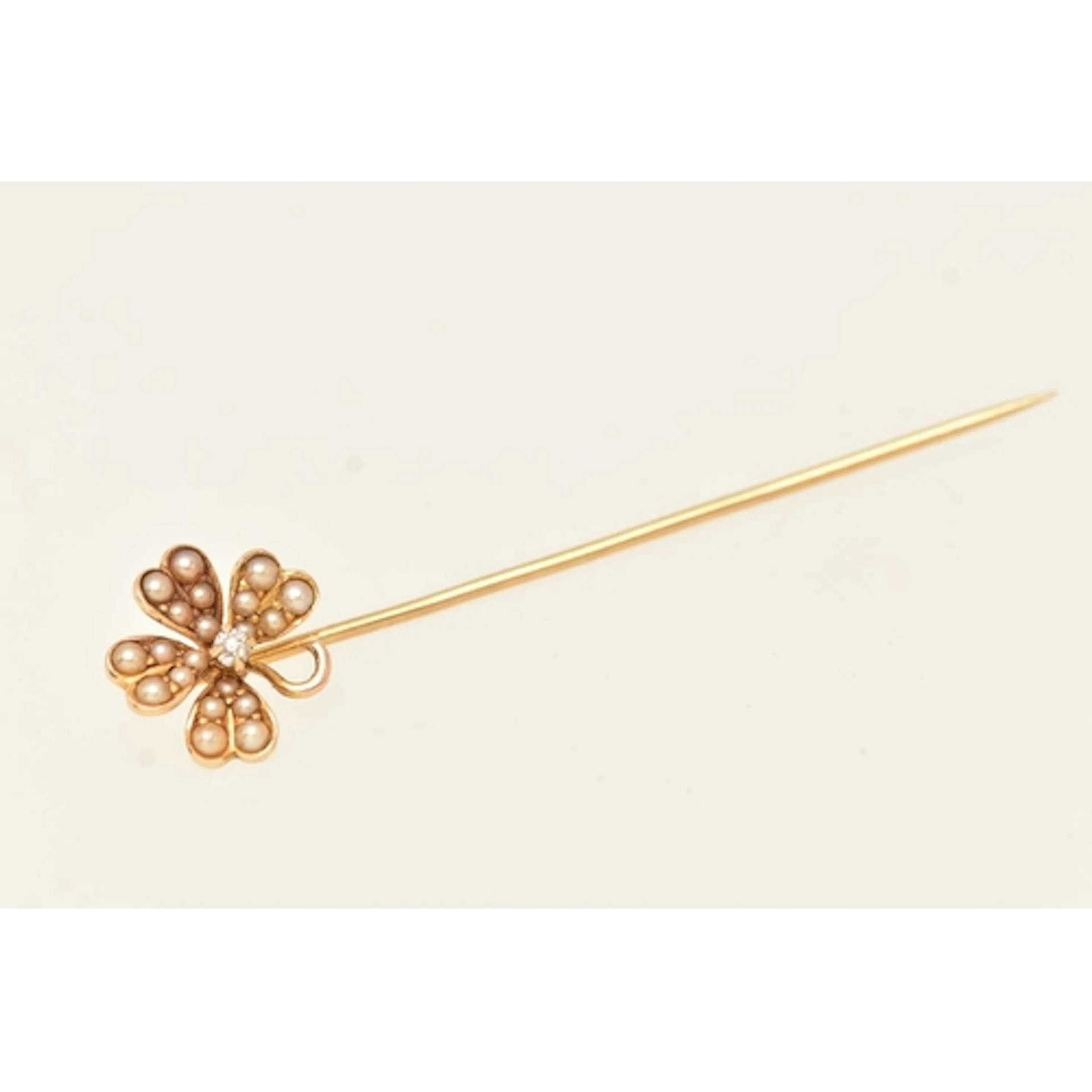 A YELLOW METAL STICK PIN, a floral stick pin set with seed p...