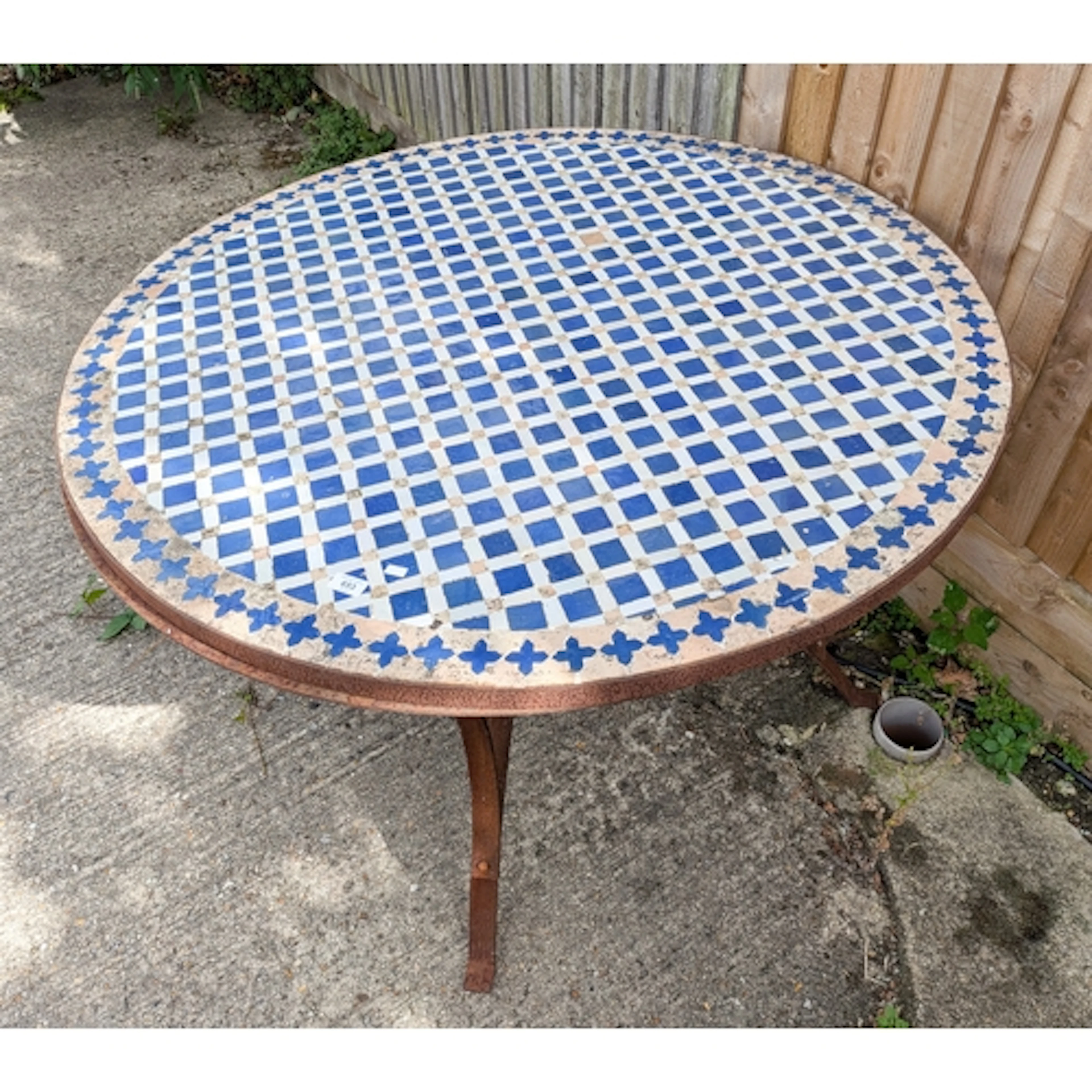 An antique style iron circular garden table with blue and wh...