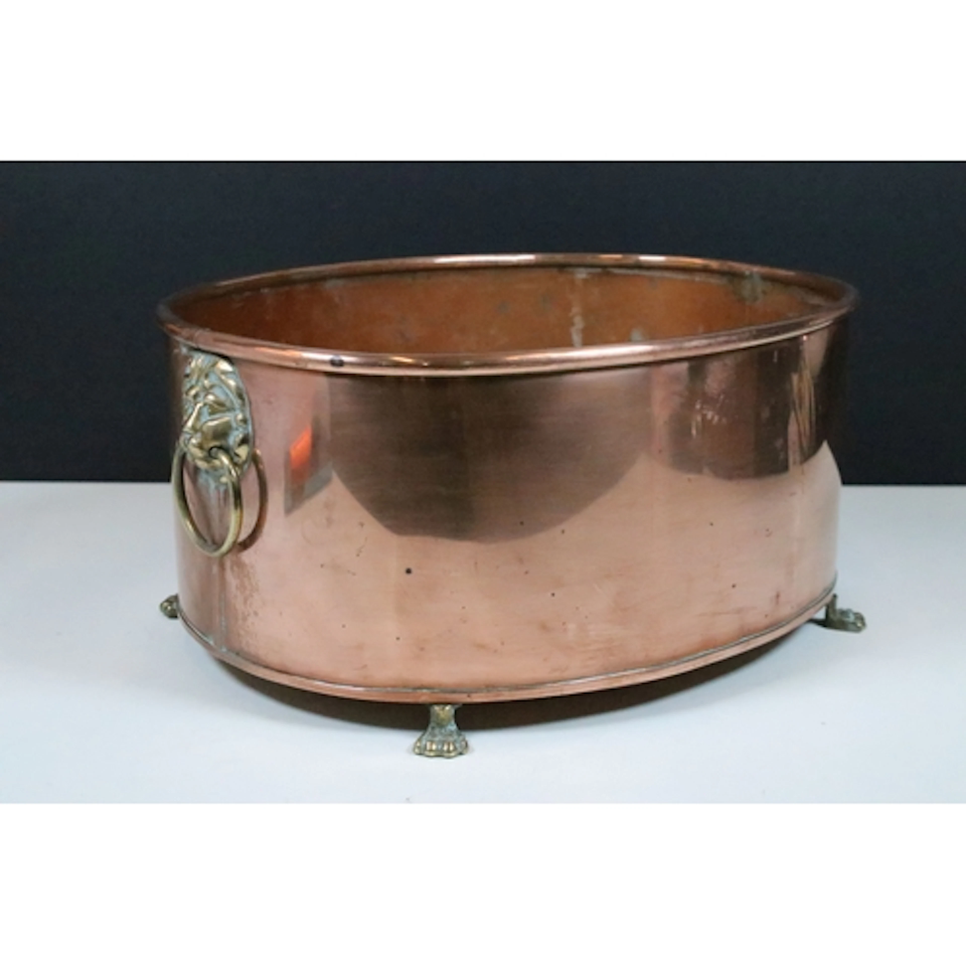 Copper oval planter with rolled rim, brass lion mask drop ri...