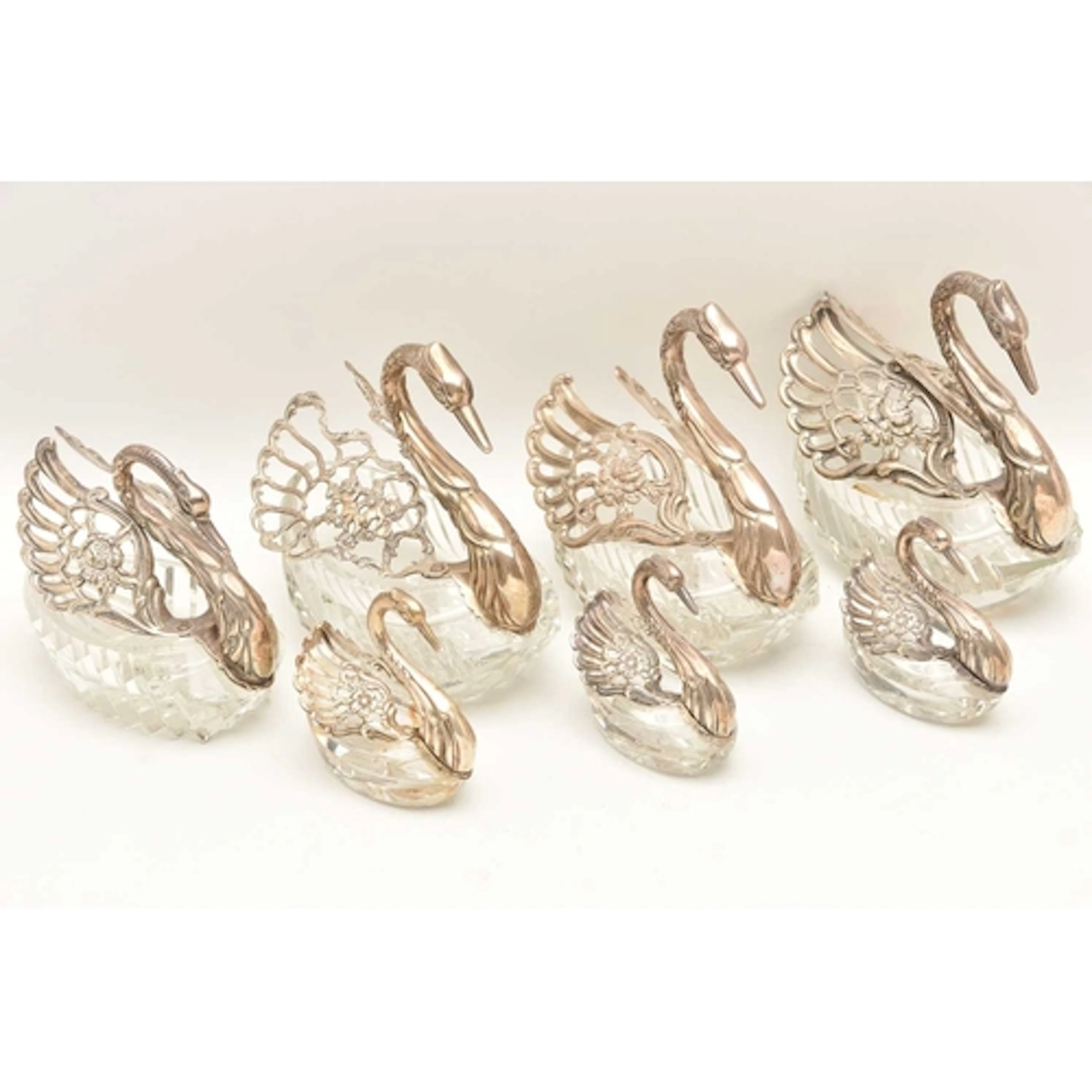 SEVEN SILVER AND WHITE METAL WINGED GLASS SWAN SALTS, to inc...