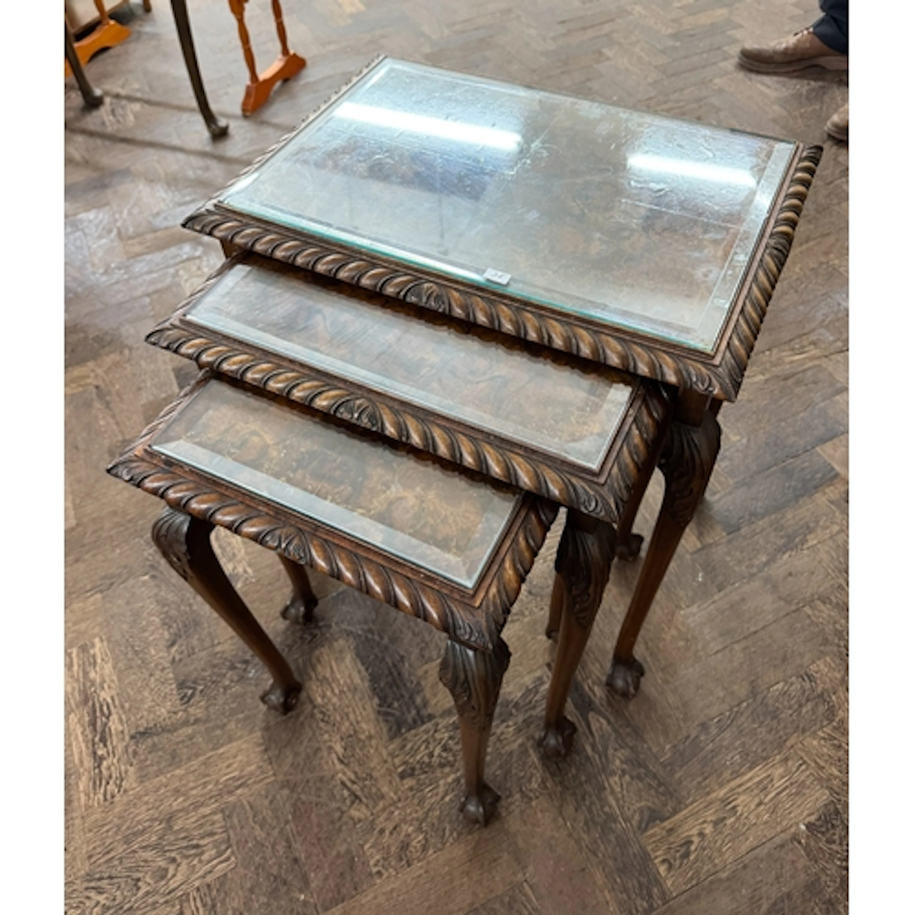 A nest of three figured walnut coffee tables standing on cla...
