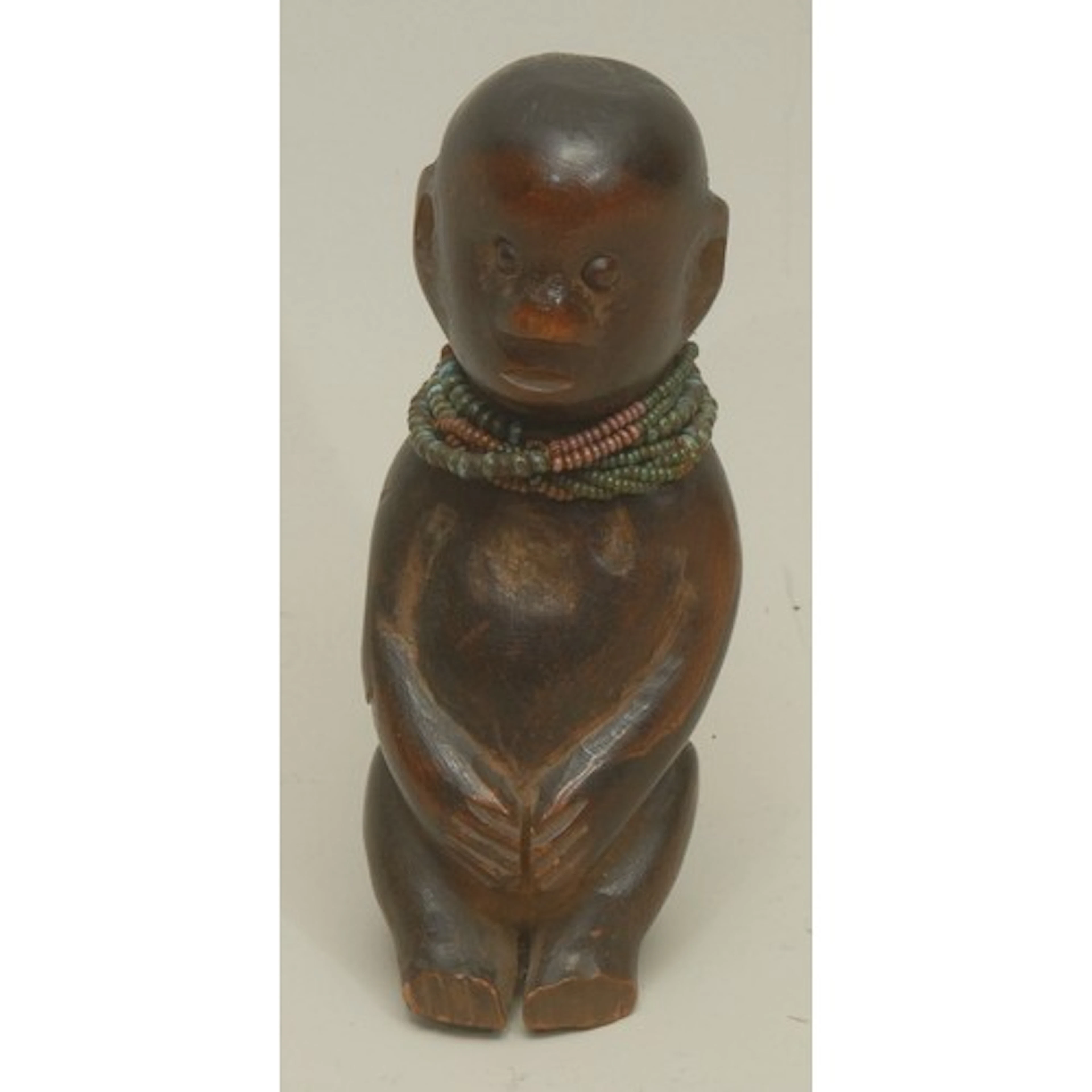 Tribal Art - a small dark patinated treen seated figure, tur...